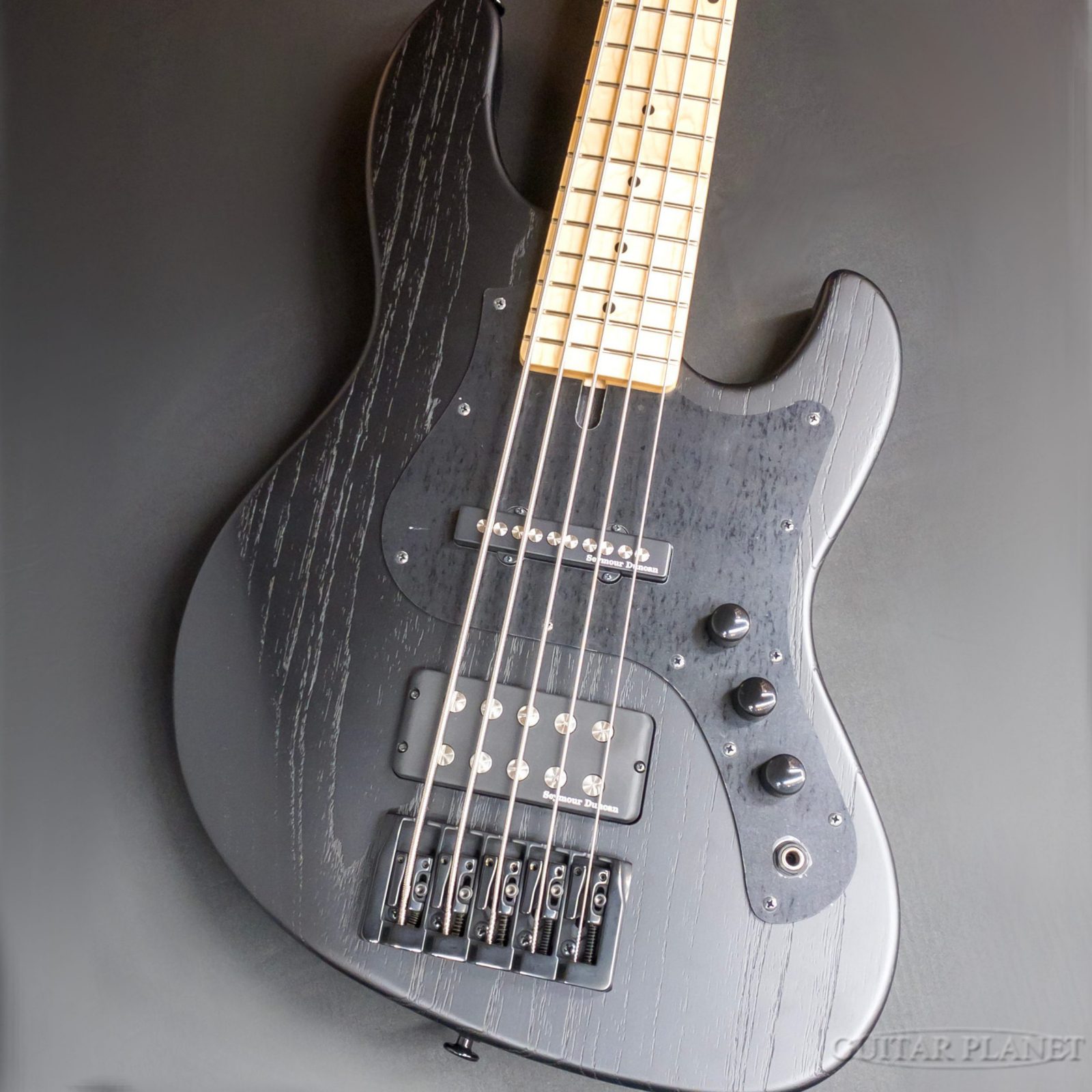精密な製造技術と安定した品質で世界的に評価される老舗ブランド「FGN」。その確かなクラフトマンシップから生み出された、モダン・プレシジョンベース「JMJ52B-ASH-M」のご紹介です。 ボディにはアッシュ材を採用し、レンジの広い明瞭なトーンと芯のある低音を実現。メイプルネックとメイプル指板の組み合わせにより、輪郭のはっきりした抜けの良いサウンドを生み出し、アンサンブルの中でも存在感を発揮します。 フレットにはFGN独自の「サークル・フレッティング・システム（C.F.S.）」を搭載。円弧状に打ち込まれたフレット構造により、弦が常に直角に接触し、正確なピッチと安定感のある響きを実現。繊細なフレーズから力強いリフまで、幅広い演奏スタイルに対応します。 ピックアップはフロントにシングルピックアップ、リアにはハムバッカータイプのピックアップを搭載。 圧倒的なパワーを含んだサウンドながら、ピックアップの音量バランスのセッティングやトーンノブを引き上げた時のコイルタップ切り替えにより器用に立ち回ることが可能なモデルです。 実用性と洗練されたルックスを兼ね備えたFGN「JMJ52B-ASH-M」。ステージからスタジオまで確かなパフォーマンスを支える、国産モダン・プレシジョンベースの一本です。是非この機会にご検討くださいませ。 SPEC Body: Ash Neck: Maple Neck Scale: 34" Fingerboard: Maple Number of Fret: 22,Medium Jumbo C.F.S. Pickups: Seymour Duncan Quarter-Pound SPB-3 Control: 2Vol,1Tone Case: Soft Case Weight: 4.59kg Serial Number: B260020 Our store is a tax-free shop. If you have any questions, please feel free to ask. Mail:bass@guitarplanet.co.jp ※掲載画像は、カメラの特性やディスプレイなどの影響により、実際に肉眼で見える色合いと差がある場合がございます。 当店でご購入頂きましたベース本体は、保証期間問わず無料にて点検・調整いたします。 なお、保証は日本国内での使用に限ります。 Store/Factory Warranty is applied only in Japan. 詳しくは、お気軽にお問合せくださいませ。