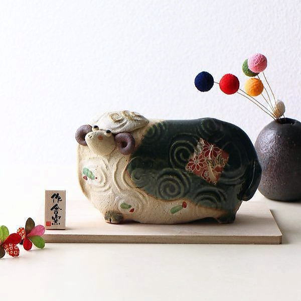 干支小物 たたら作りの「未」のお正月飾りは 手びねりの柔らかなフォルムの 愛嬌のあるヒツジさん 織部釉を施した背に 可愛い絵付けがアクセント 工芸品らしい味わいのある置物です コンパクトなサイズは 玄関・リビング・飾り棚など 気軽に飾れる干支の置物です 商品詳細 商品名 たたらの未のお正月飾り 大 商品番号 ksn2711 全体サイズ 幅18×奥行10.5×高さ8.5 材質 陶器 重量 310g 生産国 日本 ※サイズ・重量はおおよその値です 　一つずつ手作業での生産につき多少の違いはご了承ください 陶器（土物）の特性とお願い 土物は同じ技法、同じ窯で焼成しても土や釉薬に含まれる天然鉱物などの影響や天候で焼き上がりは微妙に異なります。工業製品のように同一の物になる事はありません。 手作りの不均一性、窯変、釉薬の細かいヒビ（貫入）や垂れ等は製造元より、土物の特性として良品の扱いとなります。ご理解頂きお買い求めくださいますようお願い申し上げます。 - 備考 - ひとつひとつ手作りの為、色や形に個体差がみられます ディスプレイによる色の違いはご了承下さい >> 「お正月・干支小物・縁起物」はこちら >> 「置物・オブジェ」はこちら >> 「こだわりギギらいふ」はこちら陶土を板状にして形を作る タタラ作りの未の置物 全体サイズ:幅18×奥行10.5×高さ8.5 背には和紙のような華やかな絵付けが 織部釉に美しく映えています まん丸の目がとってもキュート 背面です グルグル渦巻き模様で羊毛を表現 台座と木札がセットになっています