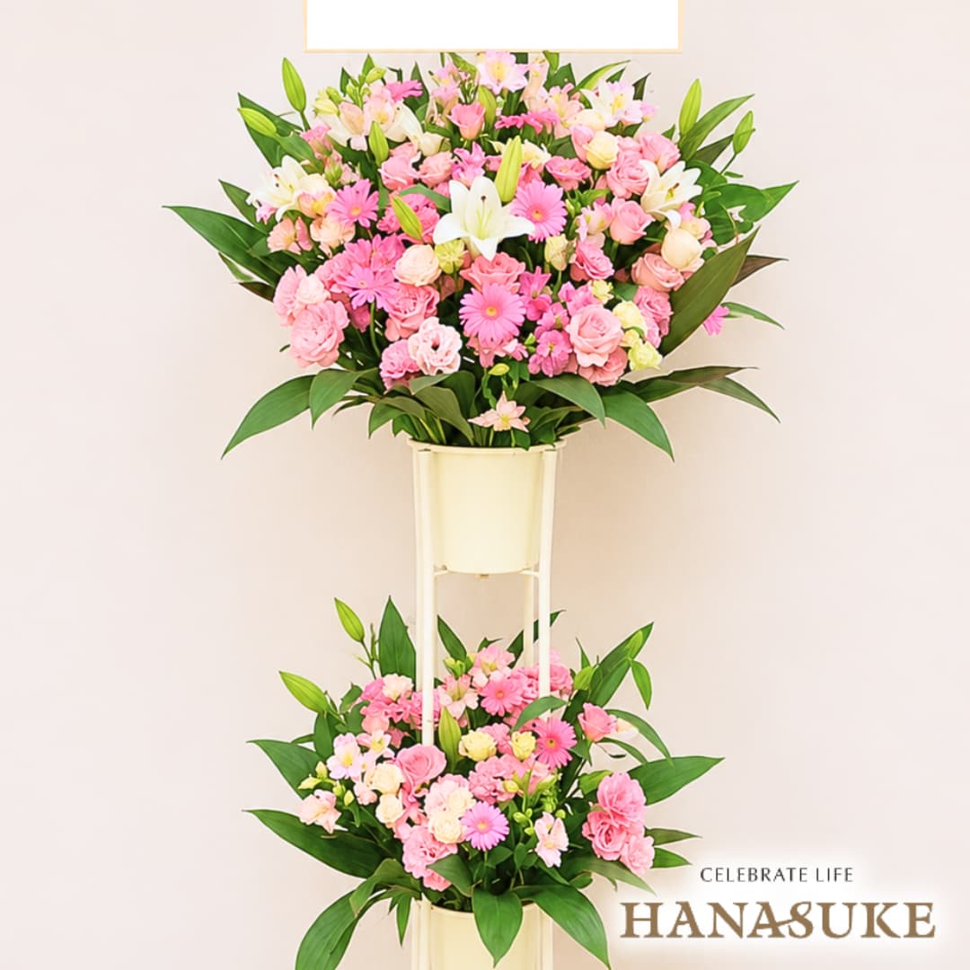 お届け商品 スタンド花 2段 お届け日 仕入れの関係上、1週間ほどお日にちをいただいております。お急ぎの場合は事前にご連絡ください。 使用花材 季節の花をメインにユリを入れておまかせで制作いたします。(ユリの色、本数はおまかせになります。) サイズ 幅約100cm×高さ約180cm ※あくまでも目安です。制作内容により異なります。 お届け内容 オアシス入り専用バケツにスタンド台付き。バケツ部とスタンド台は後日花屋が回収に伺います。 配送方法 全国の優良花屋から手渡しでお届けします。ただし、当店のネットワーク基準に合った花屋のない地域はお届けできない場合がございます。 送料 花助は全国の都市部にある花屋を厳選したフラワーネットワークになります。 都市部であれば送料無料でお届け可能です。 ただ、都市部から離れた郊外へお届けの際は【配送料1,650円（税込）】がかかる場合があります。 ご注文後、配送料については電話もしくはメールにてその旨ご連絡させていただきますのでご安心ください。 無料サービス スタンド花の設置・回収 / 名札 / 配達完了報告 / 画像報告(※画像報告は希望者のみ、配達後5日程度) / 見積書・請求書・領収書全国の花贈りに精通したフラワーコンシェルジュが、お客様一人ひとりのご用途に合った、 満足度の高い花屋をその都度厳選し、最高のフラワーギフトを提供します。