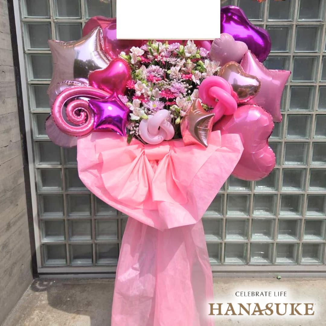 お届け商品 【リボン付き】ドレス・バルーンスタンド花 1段 お届け日 仕入の関係上、お届けに2〜5日程お日にちを頂く場合がございます。 使用花材 季節の花をメインにおまかせで制作いたします。 サイズ 幅約100cm　x　高さ約180cm　あくまでも目安です。制作内容により異なります。 お届け内容 オアシス入り専用バケツにスタンド台、リボン・ドレス付き。(リボンとドレスの色にご指定がある場合は備考欄へご入力ください。色によってはご対応できない場合もございます。) バケツ部とスタンド台は後日花屋が回収に伺います。 配達エリア 特別対応エリアをご確認ください。但し、注文内容や配達状況によってはお届けが出来ない場合もございます。予めご了承くださいませ。 送料 花助は全国の都市部にある花屋を厳選したフラワーネットワークになります。 都市部であれば送料無料でお届け可能です。 ただ、都市部から離れた郊外へお届けの際は【配送料1,650円（税込）】がかかる場合があります。 ご注文後、配送料については電話もしくはメールにてその旨ご連絡させていただきますのでご安心ください。 無料サービス スタンド花の設置・回収 / 名札 / 配達完了報告 / 画像報告(※画像報告は希望者のみ、配達後5日程度) / 見積書・請求書・領収書 注意 商品ページに掲載されている画像は過去にお届けした一例であり、商品のサンプルではありません。季節・地域によって仕上がりは異なります。予めご了承ください。全国の花贈りに精通したフラワーコンシェルジュが、お客様一人ひとりのご用途に合った、 満足度の高い花屋をその都度厳選し、最高のフラワーギフトを提供します。