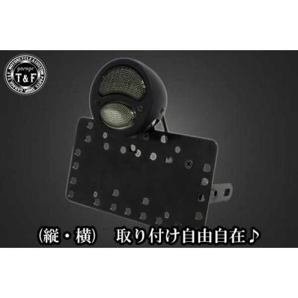 SN0193 ガレージT&F サイドナンバーキット&DUOテールランプ(デュアル)黒(スモークレンズ)+ステー DS1100/DSC1100ヤマハ ドラッグスター1100 / 1100クラシック(全年式)【本体の仕様】 ・素材:スチール製。 ・カラー:ブラック仕上げ。 【テールランプ取り付けステーの仕様】 ・素材: スチール製。 ・カラー:ブラック仕上げ。 【配線の役割】 ・赤色:ブレーキランプ(+)。 ・青色:ポジションランプ(+)。 ・黒色:アース(-)。 ※製造ロットによってテールランプの配線の色、長さが変更されることがございますので予めご了承ください。 【製品の特徴】 ・通常のサイドナンバーKITでは縦固定か横固定のみですが、本製品は縦横どちらにも対応。あなたのバイクスタイルに合わせた自由なレイアウトが可能です。 ・取り付けステーの角度調整や前後スライド調整が出来る為、ナンバープレートの位置を思い通りにセッティング可能。細部まで理想のスタイルを実現します。 ・横向きの場合:7か所の取り付け位置を選択可能。 ・縦向きの場合:12か所の取り付け位置を選択可能。 ・車種専用のステー付きです。加工不要で取り付け可能。 ガレージT&F製フラットフェンダーKITと同時装着される場合はサイドナンバーオフセットKITを同時にお買い求め下さい。 【注意事項】 ・ガレージT&F製サイドナンバーKITは取り付け位置にかなり自由度がございます。しかしながらテールランプの種類によっては取り付け位置が制限される場合がございます。 ・ガレージT&F製フラットフェンダーKITと同時装着する場合も取り付け位置が制限される場合がございます。 ・車種によっては、別売のサイドナンバーオフセットKITが必要となる場合がありますのでご注意ください。 ・装着イメージは画像は全てドラッグスター400となります。取り付される車種によって多少イメージが異なる場合がございます。予めご了承下さい。 商品の改良や生産工程の変更により掲載されている仕様やデザインが予告なく変更される場合がございます。 SN0193楽天 HD店