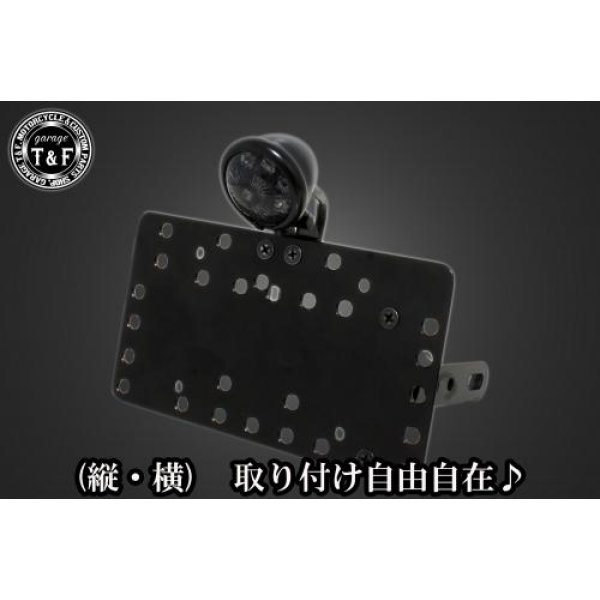 SN0713 ガレージT&F サイドナンバーキット&ブレットテールランプ(ブラック)スモークレンズ+ステー ドラッグスター1100/1100クラシックヤマハ ドラッグスター1100 / 1100クラシック(全年式)【本体の仕様】 ・素材:スチール製。 ・カラー:ブラック仕上げ。 【テールランプ取り付けステーの仕様】 ・素材: スチール製。 ・カラー:ブラック仕上げ。 【配線の役割】 ・赤色:ブレーキランプ(+)。 ・青色:ポジションランプ(+)。 ・黒色:アース(-)。 ※製造ロットによってテールランプの配線の色、長さが変更されることがございますので予めご了承ください。 【製品の特徴】 ・通常のサイドナンバーKITでは縦固定か横固定のみですが、本製品は縦横どちらにも対応。あなたのバイクスタイルに合わせた自由なレイアウトが可能です。 ・取り付けステーの角度調整や前後スライド調整が出来る為、ナンバープレートの位置を思い通りにセッティング可能。細部まで理想のスタイルを実現します。 ・横向きの場合:7か所の取り付け位置を選択可能。 ・縦向きの場合:12か所の取り付け位置を選択可能。 ・車種専用のステー付きです。加工不要で取り付け可能。 ガレージT&F製フラットフェンダーKITと同時装着される場合はサイドナンバーオフセットKITを同時にお買い求め下さい。 【注意事項】 ・ガレージT&F製サイドナンバーKITは取り付け位置にかなり自由度がございます。しかしながらテールランプの種類によっては取り付け位置が制限される場合がございます。 ・ガレージT&F製フラットフェンダーKITと同時装着する場合も取り付け位置が制限される場合がございます。 ・車種によっては、別売のサイドナンバーオフセットKITが必要となる場合がありますのでご注意ください。 ・装着イメージは画像は全てドラッグスター400となります。取り付される車種によって多少イメージが異なる場合がございます。予めご了承下さい。 商品の改良や生産工程の変更により掲載されている仕様やデザインが予告なく変更される場合がございます。 SN0713楽天 JP店