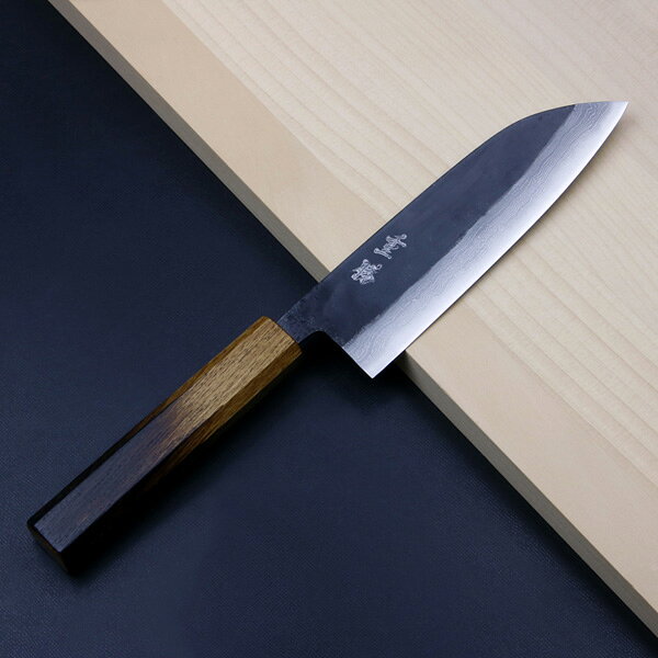 製品仕様 ■サイズ：全長約308mm 刃部 刃渡り約165mm 刃幅約46mm(刃元) 刃厚約4.5mm 柄部 長さ約130mm 幅約25.5mm(最大) 厚み約20.5mm ■重量：約160g ■材質： 刃部 切刃 青紙2号 地金 多層鋼 柄部 炙り白樫(漆塗り) ■刃の形状：両刃 ■柄の形状：八角 ■刃の仕上げ：黒打ち、ダマスカス仕上げ ■柄の仕上げ：漆塗り仕上げ ■製造：日本製 ■特徴： 土佐打ち刃物の特徴である黒打ち仕上げの刃身に特徴的な柄を組み合わせた三徳包丁です。 青紙2号の複合材を叩いて伸ばし組織を緻密にした上で最適な温度で熱処理を行うことで、切味と耐久性を兼ね備えた刃身となります。 炉で熱せられた積層材は丁寧に鍛造しており、切れ味がよい緻密な組織となった刃になっています。 1丁づつ手造りの手打ち鍛造が特徴で、刃身に現れた立体的な積層模様が美しいです。 また、丸太から製材し1〜2年掛けて自然乾燥させた白樫の表面を炙り、白樫の独自の紋様と焦がしの黒のグラデーションが特徴的な八角柄を採用。 仕上げに漆を塗ることで、耐久性と耐薬品性を持つ特徴的な柄に仕上がっています。 肉・魚・野菜とオールマイティに対応でき、家庭での最初の一本に最適。 刃だけでなく柄にも拘りのある方にお勧めの三徳包丁です。 ■切味について： 当包丁は鋼製の包丁のため、錆防止として刃物用ニスを塗布しております。 その為箱出しでご使用いただくと本来の切味より落ちます。 お使い頂くうちにニスは取れますが、研ぐことで本来の切味を体感できます。 ■注意： 手打ち鍛造品の為、刃身に傷や酸化膜の剥がれなどがある場合があります。 自由鍛造品ですので商品毎にサイズに差があり、また刃にわずかな歪みや曲りがある場合があります。 食洗機や乾燥機はご使用できません。 ハガネの包丁ですので錆びます。 黒打ち仕上げですので錆びは目立ちにくいですが、こまめに水分を拭き取ってご使用ください。