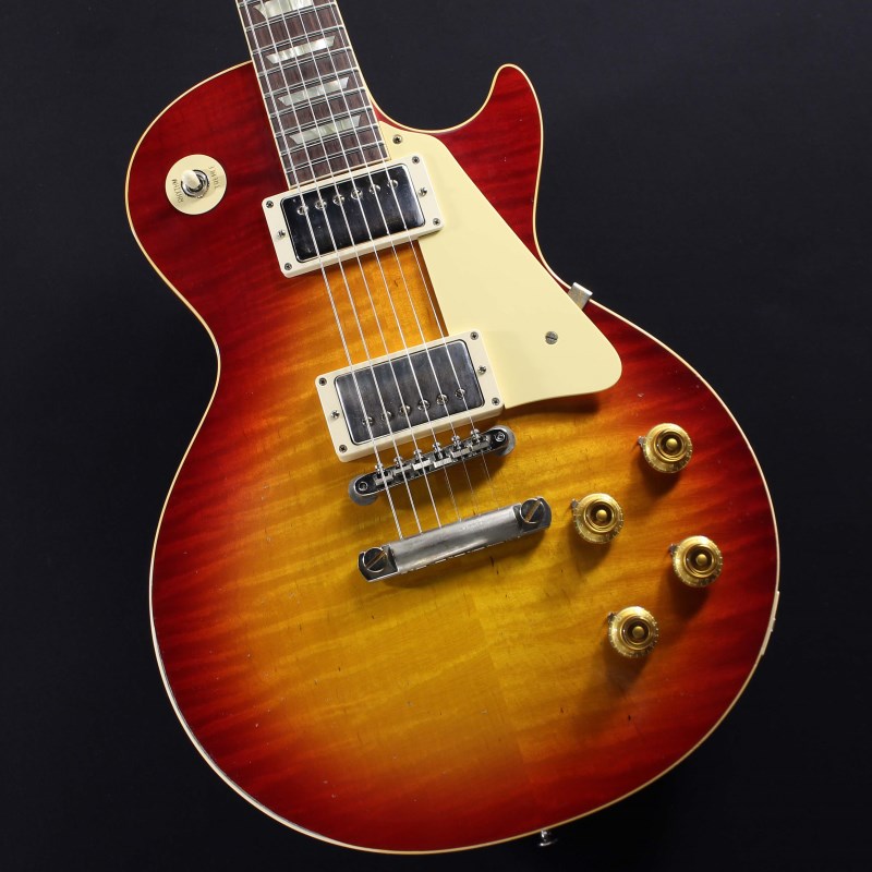 2022年にNashville Custom Shop Factoryでハンドセレクトしたトップ材を使用した1本が入荷！セレクト材ならではのリッチな表情とWashed Cherryフィニッシュによる激渋コンビネーションをぜひご堪能下さい！！長きに亘り培われた高い製作技術と飽くなき探究心、厳選されたマテリアルにより至高のエレキギター・ベースを製作するために1993年に立ち上げられたGibson Custom Shop。現在もなお昔ながらのハンドクラフト製法と、徹底的に追求したヴィンテージの知識から製作されたカスタムショップ・ラインナップは、他所の追従を許さないほどの見事な作りとなり、プレイヤーの内に秘めるインスピレーションを際限なく沸き立たせてくれる最高の愛機となるでしょう。〜Murphy Labとは〜カスタムショップ内に誕生したMurphy Lab（マーフィー・ラボ）は、ナッシュヴィルのギブソン・カスタムショップ内に新設されたラボで、科学的検証に基づく最新の技術を駆使して、ギターのエイジング（ヴィンテージ・ギターの経時変化した外観と弾き心地を再現する処理）を専門に行います。ギブソン・カスタムショップの立ち上げ時のメンバーであり、ヒストリック・コレクション開発のプロジェクト・リーダーとして尽力したトム・マーフィーは、その後新品のギターにヴィンテージのルックスとフィーリングをもたらすエイジングというテクニックで活躍してきました。トムのヴィンテージ・ギターへの情熱と深い知識に裏打ちされた技術によって、ギブソン・ギターの自然なラッカーのクラック、演奏による摩耗を見事に再現しています。トム・マーフィーとギブソンは、経時変化によりウェザーチェックと呼ばれるクラックを生じさせる、1950年代、1960年代のニトロセルロースラッカーを科学的に解析し、その変化のプロセスをひも解き、あらゆるモデルのプロトタイプによるテストを重ねて、ヴィンテージ同様のナチュラル・ウェザーチェックを再現するラッカー・プロセスを開発しました。マーフィー・ラボは、トム・マーフィーがギブソン・カスタムショップのチームを率いて、プロトタイプをもとに、あらゆるボディシェイプ、フィニッシュ、エイジング・レベルの検証を始めたことから、その構想が生まれました。その結果、これまでにないリアリティとこだわりを追求したエイジングを行うために、ギブソン・カスタムショップ内に設立されました。トム・マーフィーの存在と、その芸術的な作品の数々は、ギブソンの歴史の中で重要な役割を果たし、今もそしてこれからもマーフィー・ラボとして永遠に引き継がれていきます。本機は4段階で設けられたエイジング・レベルの中で2番目となる「Light Aged」が施された1959 Les Paul Standard。より高密度なウェザーチェックとライトエイジド・ハードウェアにより、ホームで弾かれてきたギターの経時変化、演奏による摩耗を再現本機の重量4.17kgとレスポールらしいずっしりとしたウェイト！アンプをつなぐ前から生鳴りで楽しませてくれます。1959 Les Paulならではの光の当たり方や角度で変化するボディの杢目と色合いはギブソンのゴールデンエラに作られたオールド独特のルックスとプレイフィールを再現しています。ネックシェイプは「Authentic '59 Medium C-Shape」を採用しており太すぎず細すぎず、現代的なプレイスタイルにも対応できる仕上がりとなっております。ピックアップは近年の定番モデルとなっているCustombucker Alnico IIIを継続して採用。キレのよいバイト感と個体がもたらす豊かなトーンバランスは本機でしか味わえない絶品サウンドをご体感頂けることでしょう。新たに搭載されたバンブルビータイプのペーパーオイルコンデンサーやヴィンテージカーブを追及した500KのCTSポットを装備。通常仕様の500kΩポットに比べてボリュームを絞っても極端に高域が削られず、手元の操作でクリーンサウンドからドライブサウンドまでを自在に操ることができます。10〜6のメモリまでは歪みが維持され、6〜1にかけて滑らかにダウンしていくので、ボリュームコントロールの長さによって表情豊かなプレイを可能にしています。細部にまでヴィンテージに拘りを持ったGibsonが送る最新スペックは、あなたのギターライフをより豊かにしてくれること間違い御座いません！！是非お手にとってご体感ください！！【SPEC】Body: Hand Selected 2-Piece Figured Maple Top & 1-Piece Lightweight MahoganyNeck: Solid MahoganyProfile: Authentic ’59 Medium C-ShapeFingerboard: Indian RosewoodFrets: Historic Medium-JumboNut: NylonHardware: Nickel Light AgedBridge: No-Wire ABR-1 & Lightweight Aluminum TailpieceMachinehead: Kluson ReissuePickups: Custombucker Alnico III (Unpotted)Control: 2Volume-2Tone-3way Toggle SW約4.17Kgカスタムショップ・ブラウン・ハードケース、認定書他付属イケベカテゴリ_ギター_エレキギター_Gibson_Custom Shop_新品 JAN:4570155998928 登録日:2024/01/08 エレキギター ギブソン カスタムショップ