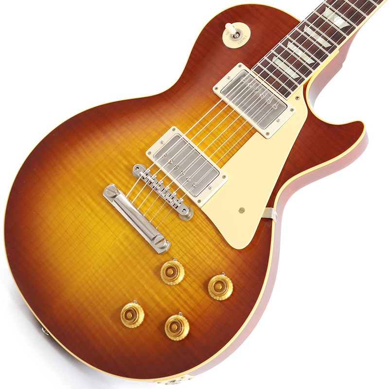 King Of Les Paul！！ 1959 Les Paul Standard Reissue VOS Iced Tea Burstが入荷！長きに亘り培われた高い製作技術と飽くなき探究心、厳選されたマテリアルにより至高のエレキギター・ベースを製作するために1993年に立ち上げられたGibson Custom Shop。現在もなお昔ながらのハンドクラフト製法と、徹底的に追求したヴィンテージの知識から製作されたカスタムショップ・ラインナップは、他所の追従を許さないほどの見事な作りとなり、プレイヤーの内に秘めるインスピレーションを際限なく沸き立たせてくれる最高の愛機となるでしょう。究極のリイシューモデルとして2015年に登場したTrue Historicスペックを大部分で踏襲した2018年仕様をベーシックに、細部に亘りさらなる拘りを持ってリファインされた最先端のカスタムショップ製Les Paul Standard。まさに「顔」とも呼ぶべきヘッドの「Les Paul MODEL」シルクスクリーンの色合いの見直しの他、Gibsonロゴデザインもよりオリジナルに近い、エッジ感のあるデザインに変更。インレイは指板ポジションマークも含め、着色によるものではなく元々色合いの濃いセルロース素材を使用することで一層雰囲気を高めています。市場での人気が高いものの流通数の少ないIced Tea Burstカラーとの組み合わせが改めて59レスポールの美しさを物語っている本機。3.86kgいうレスポールとしてはやや軽めのウェイトで取り回しも良く、芳醇な生鳴りがアンプにプラグインする前から貴方を楽しませてくれるでしょう！1959 Les Paulならではの光の当たり方や角度で変化するボディの杢目と色合いはギブソンのゴールデンエラに作られたオールド独特のルックスとプレイフィールを再現しています。昨今の1959モデルというとMurphy Labによるエイジング加工が定番となっておりますが当モデルはVOS塗装となっておりウェザーチェックなどが入っていない艶を抑えたグロス仕上げとなっております。金属パーツはサビやくすみを再現しているためウェザーチェックやエイジング加工がお好みでない方には見逃せないオススメの一本となります。ネックシェイプは「Authentic '59 Medium C-Shape」を採用しており太すぎず細すぎず、現代的なプレイスタイルにも対応できる仕上がりとなっております。ピックアップは近年の定番モデルとなっているCustombucker Alnico IIIを継続して採用。キレのよいバイト感と個体がもたらす豊かなトーンバランスは本機でしか味わえない絶品サウンドをご体感頂けることでしょう。新たに搭載されたバンブルビータイプのペーパーオイルコンデンサーやヴィンテージカーブを追及した500KのCTSポットを装備。通常仕様の500kΩポットに比べてボリュームを絞っても極端に高域が削られず、手元の操作でクリーンサウンドからドライブサウンドまでを自在に操ることができます。10〜6のメモリまでは歪みが維持され、6〜1にかけて滑らかにダウンしていくので、ボリュームコントロールの長さによって表情豊かなプレイを可能にしています。3.86kgというウェイトから放たれる音は生音から良く鳴り、振動がボディからネックにかけてしっかりと伝わってきます。ディストーションサウンドから甘いクリーントーンまでこの1本で全てを網羅できると感じさせてくれるサウンドとなっております。細部にまでヴィンテージに拘りを持ったGibsonが送る最新スペックは、あなたのギターライフをより豊かにしてくれること間違い御座いません！！是非お手にとってご体感ください！！■Weight≒3.86kg■S/N:9 32345【SPEC】Body:2PC Maple Top/Mahogany BackNeck:Mahogany w/Long TennonProfile: Authentic ’59 Medium C-ShapeFingerboard:RosewoodFrets:Historic Medium-JumboNut:NylonHardware:Nickel AgedBridge:No-Wire ABR-1 & Lightweight Aluminum TailpieceMachinehead:Kluson ReissuePickups:Custombucker Alnico III (Unpotted)Control:2Volume-2Tone-3way Toggle SWカスタムショップ・ブラウン・ハードケース、認定書他付属イケベカテゴリ_ギター_エレキギター_Gibson_Custom Shop_新品 JAN:4580568415196 登録日:2023/07/28 エレキギター ギブソン カスタムショップ