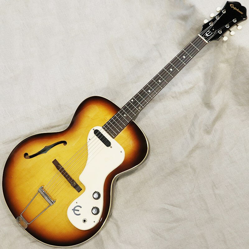 現在ではGibson（ギブソン）の姉妹ブランドとしておなじみのEpiphone（エピフォン）ですが、1950年代後半のギブソン社による買収以前は、特にアーチトップの分野においてギブソンのライバルとして躍動していた歴史あるブランドであります。ギブソン買収以降は、ソリッドボディモデルの生産も始まり、世界中のギターファンに愛される魅力的なモデルが多数誕生しました。ギブソン工場生産時期のエピフォンモデルですね。ギブソンでいうES-120Tとほぼ同様の仕様を持ちます。16インチ幅のシンラインボディ、ラミネイトメイプルトップ＆バックのセンターブロックなし構造、メロディメーカースタイルのシングルコイルピックアップ、コントロール系と一体型の立体的なピックガードといった独特の仕様が特徴的ですね。【ボディ】全体重量は約2.5kg。ボディ材はメイプル。ギブソンモデルと比べるとカッタウェイ付近のバースト具合がすっきりとしたサンバーストカラーが特徴です。細かなキズ、若干のウェザーチェック、ピックガードのステッカー跡、パーツのくすみはみられるものの、とてもきれいなコンディションをキープしております。当時のモデルタグはとても貴重です。【ネック】ネック材はマホガニー1ピース。ヘッドまわりの若干の打痕はみられますが、ボディ同様かなりきれいなコンディションをキープしております。チューナーは巻き具合の固さにそれほどバラつきはみられず、しっかりと機能します。フレット／ナットは少々の減り程度で、プレイアビリティは良好です。ナット幅42.0mm。比較的しっかりとしたネックシェイプが特徴です。【電装系】コントロールはシンプルな【ボリューム／トーン】となります。ピックアップはES-120Tやメロディメーカーにも採用されるギブソンシングルコイルを1基装備。ボディの生鳴りが素晴らしく、ビザール系にも通ずる倍音感豊かなギラっとしたトーンが魅力です。付属ケース：ノンオリジナルエピフォンハードケースWeight：2.5kgBody Material（Top／Rim／Back）：Laminate Maple／Laminate Maple／Laminate MapleNeck Material／Scale length：Mahogany 1 piece／624mm（24-1/2inch）Bridge／Tail：Rosewood bridge＆Saddle／Trapeze Tailpiece， NickelFingerboard／Fret Marker／Radius：Rosewood／Pearloid Dot／304.8mm（12inch）Nut Width／Fret Size（Width）：42.0mm／2.7mm， 20 FretNeck Thickness（1F／7F／10F）：21.5mm／23.6mm／24.4mmPickup：Gibson Single Coil（7.3kΩ）※ピックアップの直流抵抗値はコントロール部を通しての計測となります-------Heartman Vintage Guitarsは池部楽器店のヴィンテージ・ギター＆ベースの専門店です-------イケベカテゴリ_ギター_エレキギター_Epiphone_アーチトップ_ヴィンテージ JAN:2500010158671 登録日:2024/05/08 エレキギター エピフォン セミアコ フルアコ