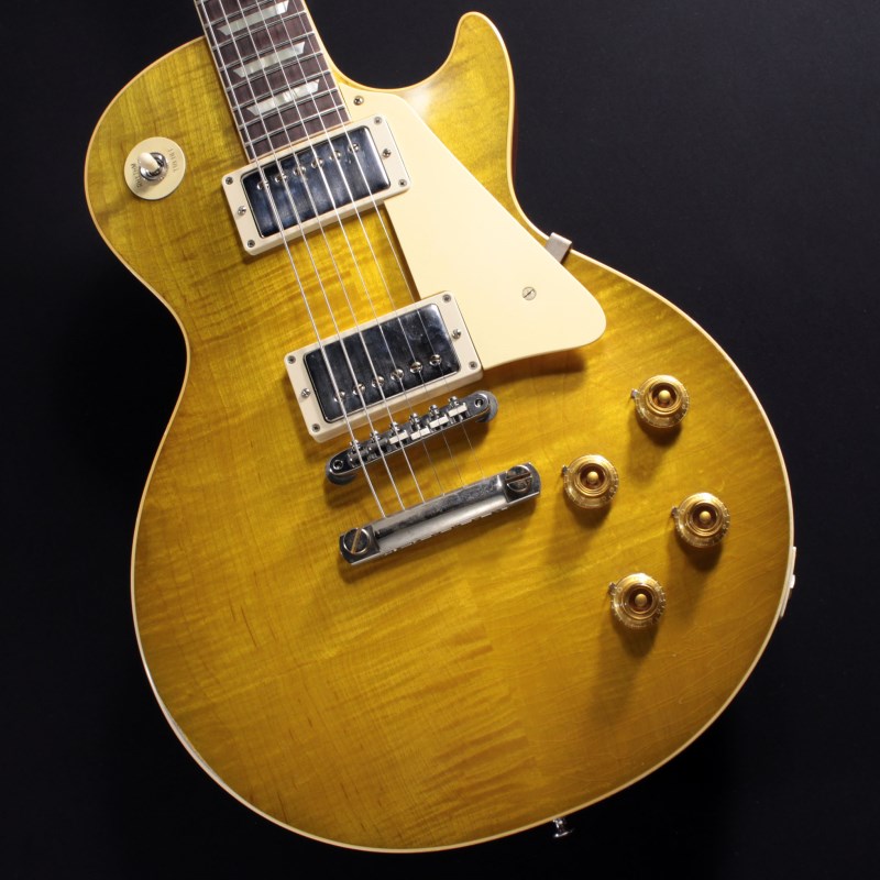 2022年にNashville Custom Shop Factoryでハンドセレクトしたトップ材を使用した1本が入荷！セレクト材ならではのリッチな表情とGreen Lemon Fadeフィニッシュによる激渋コンビネーションをぜひご堪能下さい！！長きに亘り培われた高い製作技術と飽くなき探究心、厳選されたマテリアルにより至高のエレキギター・ベースを製作するために1993年に立ち上げられたGibson Custom Shop。現在もなお昔ながらのハンドクラフト製法と、徹底的に追求したヴィンテージの知識から製作されたカスタムショップ・ラインナップは、他所の追従を許さないほどの見事な作りとなり、プレイヤーの内に秘めるインスピレーションを際限なく沸き立たせてくれる最高の愛機となるでしょう。本機は4段階で設けられたエイジング・レベルの中で2番目となる「Light Aged」が施された1959 Les Paul Standard。「ライト」とはいってもヘッド先端からボディエンドに至るまで要所要所に傷が入れられ、さらに経年によって生じるウェザーチェックも本当に60年以上経過したかのような雰囲気で施されております。スペックとしては毎年のアップデートを経た最新のヒストリックコレクションがベースとなっておりますので、アンポッテッド仕様のCustombucker Alnico 3ピックアップをはじめとするエレクトロニクスにはビンテージカーブを追求したCTSポットやバンブルビーレプリカのコンデンサを採用。重厚なサウンドイメージが強いLes Paulですが、トゥルーヒストリック以降は暖かみのある中低域を持ちながらも煌びやかで艶のある高音が強調された印象で、クリーンやクランチで弾くと非常に心地良く響いてくれるようなサウンドが特徴です。ハードロック的なディストーションでも存在感のあるサウンドをアウトプットいたしますが、エフェクターは多用せずにアンプ直で弾いて頂いたほうが本機の素晴らしさを感じて頂けるでしょう。もちろん、ハードウェアやプラスチックパーツにはトゥルーヒストリックパーツを採用。素材、形状、製法まで徹底的にビンテージパーツを研究して作り上げただけあり、その見事なまでのエイジングと相まって究極ともいえるリアルな外観を演出しております。ルックス、サウンドともに「完成形」といっても過言ではない、珠玉の1本を是非ご堪能下さい。〜Murphy Labとは〜カスタムショップ内に誕生したMurphy Lab（マーフィー・ラボ）は、ナッシュヴィルのギブソン・カスタムショップ内に新設されたラボで、科学的検証に基づく最新の技術を駆使して、ギターのエイジング（ヴィンテージ・ギターの経時変化した外観と弾き心地を再現する処理）を専門に行います。ギブソン・カスタムショップの立ち上げ時のメンバーであり、ヒストリック・コレクション開発のプロジェクト・リーダーとして尽力したトム・マーフィーは、その後新品のギターにヴィンテージのルックスとフィーリングをもたらすエイジングというテクニックで活躍してきました。トムのヴィンテージ・ギターへの情熱と深い知識に裏打ちされた技術によって、ギブソン・ギターの自然なラッカーのクラック、演奏による摩耗を見事に再現しています。トム・マーフィーとギブソンは、経時変化によりウェザーチェックと呼ばれるクラックを生じさせる、1950年代、1960年代のニトロセルロースラッカーを科学的に解析し、その変化のプロセスをひも解き、あらゆるモデルのプロトタイプによるテストを重ねて、ヴィンテージ同様のナチュラル・ウェザーチェックを再現するラッカー・プロセスを開発しました。マーフィー・ラボは、トム・マーフィーがギブソン・カスタムショップのチームを率いて、プロトタイプをもとに、あらゆるボディシェイプ、フィニッシュ、エイジング・レベルの検証を始めたことから、その構想が生まれました。その結果、これまでにないリアリティとこだわりを追求したエイジングを行うために、ギブソン・カスタムショップ内に設立されました。トム・マーフィーの存在と、その芸術的な作品の数々は、ギブソンの歴史の中で重要な役割を果たし、今もそしてこれからもマーフィー・ラボとして永遠に引き継がれていきます。約4.2kgカスタムショップ・ブラウン・ハードケース、認定書他付属Body: Hand Selected 2-Piece Figured Maple Top & 1-Piece Lightweight MahoganyNeck: Solid MahoganyProfile: Authentic ’59 Medium C-ShapeFingerboard: Indian RosewoodFrets: Historic Medium-JumboNut: NylonHardware: Nickel Light AgedBridge: No-Wire ABR-1 & Lightweight Aluminum TailpieceMachinehead: Kluson ReissuePickups: Custombucker Alnico III (Unpotted)Control: 2Volume-2Tone-3way Toggle SWイケベカテゴリ_ギター_エレキギター_Gibson_Custom Shop_新品 JAN:4570155998966 登録日:2023/10/19 エレキギター ギブソン カスタムショップ