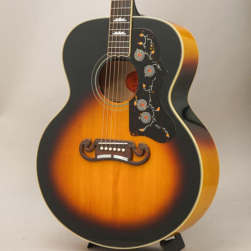 ■商品紹介ギブソンSJ-200(TM)は1937年に登場し、その存在感のあるボディサイズ、上質なサウンド、豊かな音量、そしてひと目でわかる存在感によって、キング・オブ・フラットトップの愛称で知られるようになりました。初期のモデルにはローズウッド材が使用されていましたが、1947年にはサイド＆バック材がメイプルに変更されました。カウボーイの名優からフォーク詩人、カントリー・シンガーからロック界の大物まで、あらゆるプレイヤーに愛されてきたSJ-200は、ヴィンテージ市場でも非常に高い人気を誇っています。このたびエピフォンは、ギブソン・カスタムとの緊密な連携により、1957年製スーパージャンボ・モデルを復刻したInspired by Gibson Customシリーズ1957 SJ-200 Reissueをリリースします。本モデルにはヴィンテージ・モデルの仕様の特徴が随所に取り入れられています。ボディ側について、オール単板構造、サーマリー・エイジド加工が施された単板のシトカスプルース・トップ、スキャロップドXブレーシング、単板のフィギュアド・メイプルによるサイド＆バック、トップ＆バックでの多層バインディングが採用されています。ネックはウォルナット材のストリンガーを挟んだフレイム・メイプルによる2ピース構造で、Cシェイプ・プロファイルを採用。指板にはバインディングが巻かれたインディアン・ローズウッドが使用され、マザー・オブ・パールのクラウン・インレイと20本のスタンダード・フレットが配置されています。ネックとボディの接合には、伝統的技法であるダブテイル・ジョイントを採用。SJ-200スタイルのピックガードにはヴィンテージ機さながらのデザインを採用。ローズウッド材のマスターシュ(TM)ブリッジにはマザー・オブ・パールのインレイが施されています。ナット、コンペンセイテッド・サドル、ブリッジピンにはいずれもボーン材を使用。ギブソンと同デザインのオープンブック形ヘッドストックにはバインディングが巻かれ、マザー・オブ・パールのエピフォン・ロゴとギブソンのクラウン・インレイが埋め込まれています。ヘッド裏にはInspired by Gibson Customのダブル・ダイヤモンド・ロゴが刻まれ、Antique Naturalカラーのモデルのみ、ネック裏にてスティンガー・ヘッドストックを採用。現代のミュージシャンのニーズに応え、L.R. Baggs(TM) Element Bronze VTCピックアップとアクティブ・プリアンプを搭載。サウンドホール部に取り付けられたボリューム／トーンコントロールにより演奏中でも即座に出音の調整が可能です。Inspired by Gibson Customロゴ入りのRed Lineスタイルのハードシェル・ケースが付属します。■仕様詳細Shape | SJ-200Top | Thermally Aged Solid Sitka SpruceBack and Sides | Solid Figured MapleBracing | Scalloped X-BracingBinding | Multi-ply Top and Back， Single Ply Fretboard and HeadstockNeck | Two-Piece Flame Maple with Walnut StringerNeck Profile | C-profileNut width | 1.72 / 43.79mmFingerboard | Indian RosewoodScale length | 25.5 / 647.7mmNumber of frets | 20Nut | BoneInlay | Mother-of-Pearl Graduated CrownBridge | SJ-200 Rosewood Two Bar Moustache; Mother-of-Pearl BarsTuners | Epiphone DeluxePlating | GoldElectronics | L.R.Baggs Element Bronze VTCControls | Soundhole Mounted Volume and Toneハードケース付属検索キーワード：イケベカテゴリ_アコースティック・エレアコギター_エレアコギター_Epiphone_新品 SW_Epiphone_新品 JAN:4570156008121 登録日:2026/07/27 エレアコ エピフォン