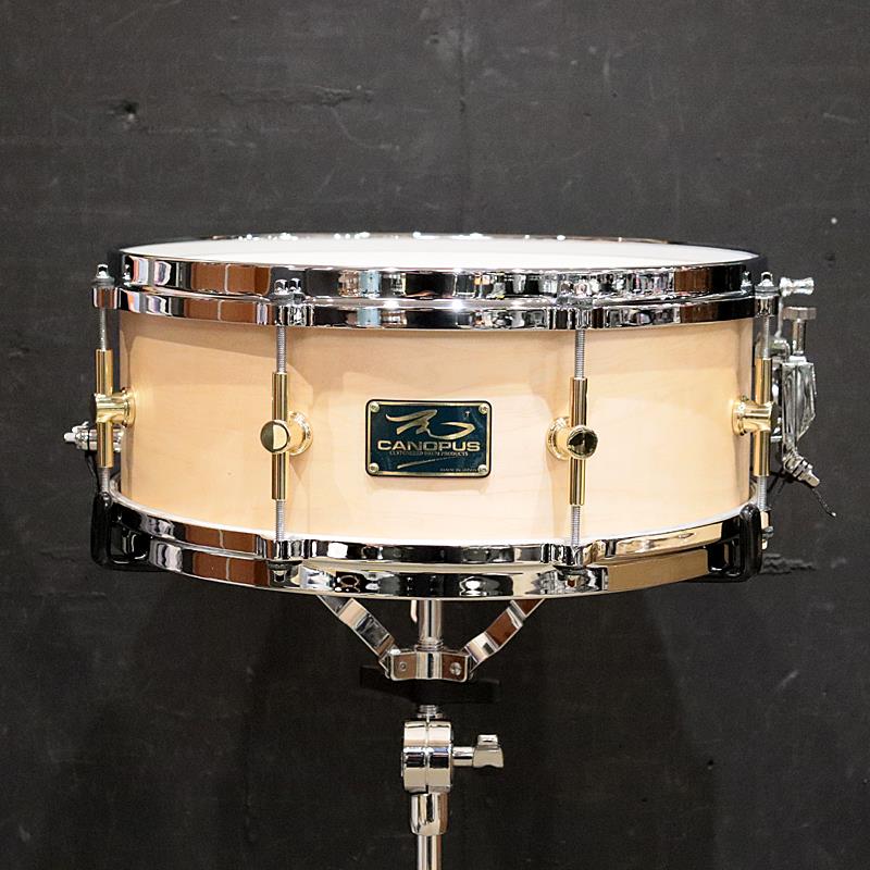 ■商品紹介＜MO Snare Drum w/Wood Hoop＞厚手のメイプルシェルは潜在的なパワーは持っていますが、鳴らしきることが難しく、ともするとアタック音ばかり目立つ薄っぺらいサウンドになりがちです。しかしこのMOは的確なベアリングエッジを施し、オイルフィニッシュで極薄の塗膜に仕上げることにより、シェルの持つパワーを効率良く引き出すことができます。また、高品質なアメリカンメイプルシェルを使用しつつも、オイルフィニッシュを採用することで材料コストの削減や生産効率の向上をはかり、そのサウンドからは想像もできない驚異的なコストパフォーマンスを実現しています。＜スペック＞サイズ：14''×5.5''シェル：10ply メイプル 8mmフィニッシュ：Natural Oilフープ / テンション数：ダイキャストフープ / 8テンションスネアワイヤー：ヴィンテージ・スネアワイヤー付属品：チューニングキー検索キーワード：イケベカテゴリ_ドラム_スネアドラム_CANOPUS_新品 SW_CANOPUS_新品 JAN:4511239005583 登録日:2026/07/29 スネア スネアドラム カノウプス カノープス