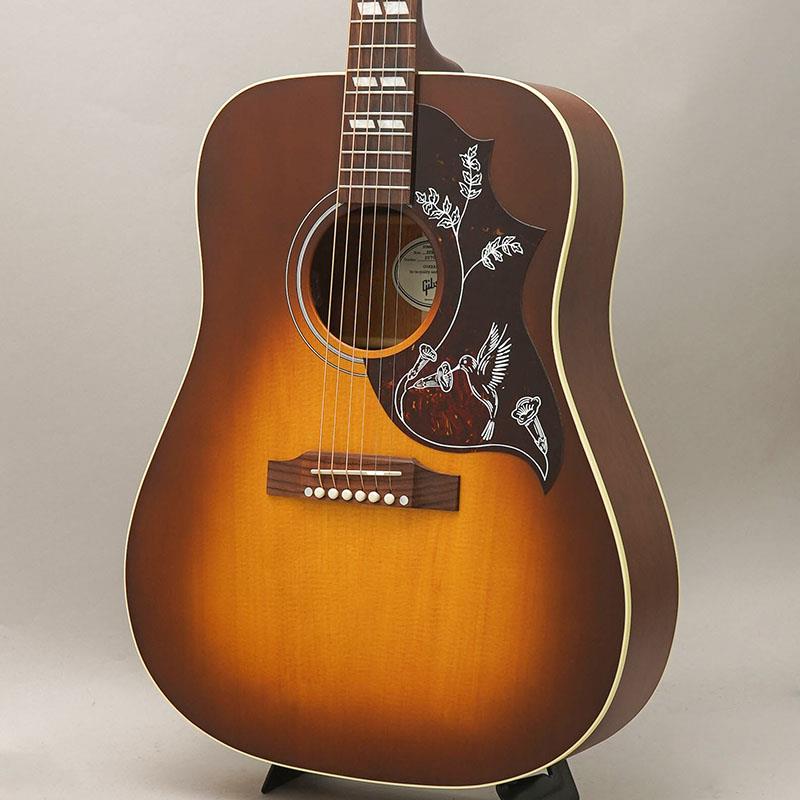■商品紹介1960年に誕生したハミングバード(TM)は、アコースティックギター史の中で最も特別で愛されたモデルの一つとして、歴史に名を残す存在となりました。この度新たにリリースされるHummingbird Specialは、モンタナ州ボーズマンの工場でギブソンの熟練ルシアーたちによって精巧に製作され、USA製のギブソン・アコースティックでありながらも、たいへん魅力的な価格を実現したモデルです。Hummingbird Specialは伝統あるスクエアショルダー・ボディを持ち、サイド＆バック材には単板マホガニー、そしてトップ材には単板シトカ・スプルースを使用しています。ボディ・トップにはギブソン伝統のスキャロップド X ブレイシングが採用されています。これらの木材によるコンビネーションにより、ウォームでバランスのとれたトーンに加え卓越したダイナミック・レンジが得られ、どのような音楽ジャンルにも対応することが可能です。Hummingbird Standardよりも薄めのボディ幅であるコンサート・デプスの採用により、他の楽器とのミックスの中でも存在感のある引き締まった低域のレスポンスを生み、さらに演奏時のボディの抱えやすさも実現しています。ユーリー材を使用したネックはダブテイル・ジョイント方式によりボディに接合され、他のギブソン・アコースティックギターと同じく、ニカワにより接着されています。ネック・シェイプには心地よい演奏を可能にするラウンド・プロファイルを採用し、12インチ・ラジアス形状の指板にはローズウッドが使用されています。さらに指板にはハミングバードと切り離せない外観要素であるパーロイドのパラレログラム・インレイが埋め込まれており、20フレットのスタンダード・フレット仕様となっています。ギブソン伝統のベリーアップ・スタイルのローズウッド・ブリッジにはTUSQ(R)サドルを搭載し、ナットもブリッジピンも同様にTUSQ(R)製品が採用されています。また、ハイクオリティなGrover(R) Rotomatic(R)チューナーが安定したチューニングを実現しています。ピックガードにはハミングバードの世界的に有名なハチドリのグラフィクスをシンプル化したデザインを採用。Hummingbird Specialのカラーはサテン・ニトロセルロースラッカーによるサテン・ヴィンテージチェリーサンバーストまたはサテン・ワインレッドからお選びいただけます。L.R. Baggs Element Bronzeアンダーサドル・ピエゾ・ピックアップ＆アクティブ・プリアンプを搭載し、ボリューム・コントロールもサウンドホール側面から簡単に操作できるため、付属のプレミアム・ソフトシェルケースから取り出した瞬間からステージでもスタジオでも即座にプレイをお楽しみいただけます。※掲載画像はサンプルとなります。■仕様詳細Body Style Square ShoulderBody Shape HummingbirdBody Material Solid MahoganyTop Solid Sitka SpruceBack Solid MahoganySide Solid MahoganyBracing Traditional Scalloped X-bracingBinding Single Ply Cream， Top and BackBody Finish Satin Nitrocellulose LacquerNECKProfile RoundScale Length 628.65 mm / 24.75 inFingerboard Material RosewoodFingerboard Radius 304.8 mm / 12 inNeck Material UtileFret Count 20Frets StandardNut Material TUSQNut Width 43.815 mm / 1.725 inInlays Pearloid ParallelogramJoint Compound Dovetail Neck-to-body Joint; Hot Hide GlueUnder Saddle Pickup L.R. Baggs Element BronzeControls Soundhole Mounted VolumeOutput Jack 1/4 EndpinPreamp L.R. Baggs Element Bronze付属品：ギグケース検索キーワード：イケベカテゴリ_アコースティック・エレアコギター_エレアコギター_Gibson_Square Shoulder_新品 SW_Gibson_新品 JAN:4570156018298 登録日:2026/06/06 エレアコ ギブソン ぎぶそん