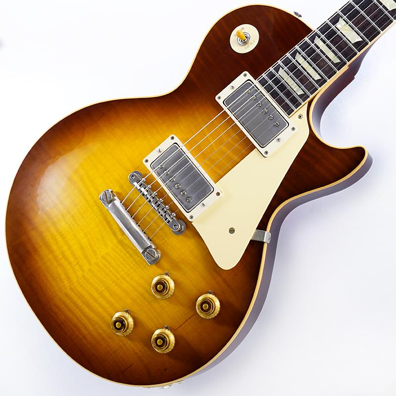 ■商品紹介King Of Les Paul！！ 1959 Les Paul Standard Reissue VOSが入荷！長きに亘り培われた高い製作技術と飽くなき探究心、厳選されたマテリアルにより至高のエレキギター・ベースを製作するために1993年に立ち上げられたGibson Custom Shop。現在もなお昔ながらのハンドクラフト製法と、徹底的に追求したヴィンテージの知識から製作されたカスタムショップ・ラインナップは、他所の追従を許さないほどの見事な作りとなり、プレイヤーの内に秘めるインスピレーションを際限なく沸き立たせてくれる最高の愛機となるでしょう。究極のリイシューモデルとして2015年に登場したTrue Historicスペックを大部分で踏襲した2018年仕様をベーシックに、細部に亘りさらなる拘りを持ってリファインされた最先端のカスタムショップ製Les Paul Standard。まさに「顔」とも呼ぶべきヘッドの「Les Paul MODEL」シルクスクリーンの色合いの見直しの他、Gibsonロゴデザインもよりオリジナルに近い、エッジ感のあるデザインに変更。インレイは指板ポジションマークも含め、着色によるものではなく元々色合いの濃いセルロース素材を使用することで一層雰囲気を高めています。1959 Les Paulならではの光の当たり方や角度で変化するボディの杢目と色合いはギブソンのゴールデンエラに作られたオールド独特のルックスとプレイフィールを再現しています。昨今の1959モデルというとMurphy Labによるエイジング加工が定番となっておりますが当モデルはVOS塗装となっておりウェザーチェックなどが入っていない艶を抑えたグロス仕上げとなっております。金属パーツはサビやくすみを再現しているためウェザーチェックやエイジング加工がお好みでない方には見逃せないオススメの一本となります。ネックシェイプは「Authentic '59 Medium C-Shape」を採用しており太すぎず細すぎず、現代的なプレイスタイルにも対応できる仕上がりとなっております。ピックアップは近年の定番モデルとなっているCustombucker Alnico IIIを継続して採用。キレのよいバイト感と個体がもたらす豊かなトーンバランスは本機でしか味わえない絶品サウンドをご体感頂けることでしょう。新たに搭載されたバンブルビータイプのペーパーオイルコンデンサーやヴィンテージカーブを追及した500KのCTSポットを装備。通常仕様の500kΩポットに比べてボリュームを絞っても極端に高域が削られず、手元の操作でクリーンサウンドからドライブサウンドまでを自在に操ることができます。10〜6のメモリまでは歪みが維持され、6〜1にかけて滑らかにダウンしていくので、ボリュームコントロールの長さによって表情豊かなプレイを可能にしています。細部にまでヴィンテージに拘りを持ったGibsonが送る最新スペックは、あなたのギターライフをより豊かにしてくれること間違い御座いません！！Weight≒3.90kgカスタムショップ・ブラウン・ハードケース、認定書他付属■仕様詳細Body:2PC Maple Top/Mahogany BackNeck:Mahogany w/Long TennonProfile: Authentic ’59 Medium C-ShapeFingerboard:RosewoodFrets:Historic Medium-JumboNut:NylonHardware:Nickel AgedBridge:No-Wire ABR-1 & Lightweight Aluminum TailpieceMachinehead:Kluson ReissuePickups:Custombucker Alnico III (Unpotted)Control:2Volume-2Tone-3way Toggle SW検索キーワード：イケベカテゴリ_エレキギター_レスポールタイプ_Gibson_Custom Shop_新品 SW_Gibson_新品 JAN:4580568415196 登録日:2026/08/13 エレキギター ギブソン カスタムショップ