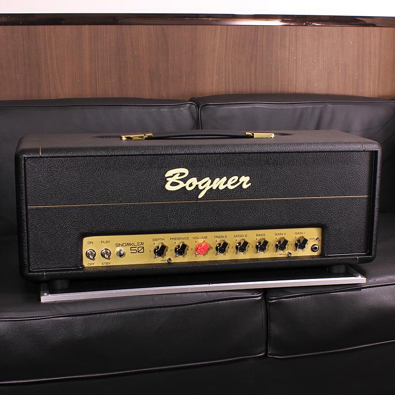 ■商品紹介【History of SNORKLER】プレイする音楽ジャンル・スタイルを問わずそのポテンシャルと存在感をひときわ発揮するブティックアンプの代名詞Bogner Amplification。ドイツで生誕したReinhold Bognerは、10代始めの頃にロックに目覚めギターを購入します。しかしギターアンプを購入するお金がなく、そこで当時サウンドエンジニアで真空管ラジオのコレクターであった父が所有するパーツを使用し、独学でギターアンプ作りを始め、その過程の中で技術やノウハウを習得していきました。その輝かしいキャリアの始まりは、最初のクライアントであるRich Williams (Kansas)がドイツでのツアー中に Reinhold Bogner が改造した1台のプレキシアンプのサウンドを気に入り、Rich Williams自身が所有するバックアップ用のプレキシアンプの改造を依頼したことから始まります。噂を聞きつけたツアーでドイツを訪れたアーティストからReinhold Bognerの元へ仕事の依頼が殺到し始め、同時期に周囲の勧めもあったことから1989年にLos Angelesに弱冠22歳で渡米を決意。今回のSNORKLER 50の原型となる自ら改造を施した50W出力の白いMarshall JCM 800「Visitenkarte」を自分の名刺代わりとして持ち込みます。そしてLAに移住後にReinhold Bognerが扉を叩いたのは、LA在住のトップミュージシャンの出入りも多かった機材のレンタル会社「Andy Brauer Studio Rentals」で、オーナーのAndy Brauerの勧めでクライアントの1人でもあったEddie Van Halenに自身が改造したマーシャルアンプを試してもらえる機会に恵まれ、そのサウンドを気に入ったEddie Van Halenは、自身が組み込んだギターと500ドルでそのアンプを入手しました。その後も多くのミュージシャンからのアンプの改造依頼を受ける中で培った知識を基に自身がデザインしたBlue pre-amp circuit boardを搭載した「SNORKLER」が誕生。オリジナルのSNORKLERは、Alice in Chainsの名盤「Facelift」でも使用されました。【フットスイッチで切り替え可能なGAIN1・2と「NOISE-GATE」「RETURN LEVEL M.V.」機能を搭載】今回、時を経て発売となったSNORKLER 50 Headは、EL34管を2本搭載した50W出力で、シンプルなコントロールノブ構成ながらもGAIN1(BLUE MODE)で作ったオーガニックでパンチーなクリーン・クランチサウンドにGAIN2(RED MODE)でゲイン量を追加することができます。GAIN1・2ノブ、BRIGHTスイッチ(※GAIN2がアクティブ時のみ有効)とパワーアンプセクションのDEPTH・PRESENCE コントロールノブ及び低音域をブーストできる「DEEP Switch」設定次第ではジューシーでアグレッシブな極上のハイゲインサウンドを作ることができます。さらに背面のコントロールパネルには、本体のスイッチでON/OFFが可能な「NOISE-GATE」と「RETURN LEVEL M.V.」を搭載。※本機のフットスイッチ端子を使用時、エフェクトループ・ノイズゲートは常時アクティブとなります。NOISE-GATE機能は、ノブを時計回りに回すとスレッショルド(threshold）が増加し、ハイゲインサウンド時のノイズを除去することが可能。RETURN LEVEL M.V.は、本機のエフェクトループがON時のみにアクティブとなり、グローバル・マスターボリュームとして使用することもできる便利な機能です。※画像はサンプルです。検索キーワード：イケベカテゴリ_ギターアンプ・ベースアンプ_ギターアンプ_ヘッド_チューブ_Bogner_新品 SW_Bogner_新品 JAN:2500070517555 登録日:2025/07/31 ギターアンプ ボグナー