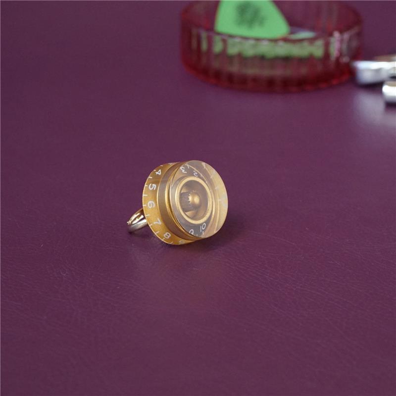 ■商品紹介■デザインギタリスト・ベーシストさんがアクセサリーに楽器やピックのモチーフを身に着けているのをよく見かけますが、だったら「つまみ」もありでしょう！ということで、作りました「ギターつまみリング」。ゴロッと大き目なサイズ感と合わせやすいシンプルカラーで、いつものファッションにも使いやすい優れもの。リング部分は印字に合わせ落ち着いたマットゴールドなので、重厚感だけでなく高級感もあります。それでいて、バンドマンだけに「！それって！」と刺さる、バンドマン探知機のようなアイテムなので、このリングがきっかけでバンドが組めちゃったりして。大き目モチーフのリングで、「音楽」も「かわいい」も存分にアピールしちゃいましょう！■サイズ・11号（フリー）・外寸　縦: 約3.5cm、横: 約2.5cm■注意事項＊こちらの商品は他ECサイトでも販売しております。在庫情報の更新は迅速を心掛けておりますが、万一ご注文時に売り切れていた際は、商品がご用意できない場合がございますのでご了承ください。＊画像の色味は屋内外の光の照射や角度により実物と異なって見える場合がございます。ご了承ください。＊一つ一つ手作りのため個体差がございます。検索キーワード：イケベカテゴリ_楽器アクセサリ_その他楽器アクセサリ_tsundrum_chan_新品 SW_tsundrum_chan_新品 JAN:4571642983106 登録日:2025/09/26 ツンドラムチャン ツン ドラム ちゃん kawaii かわいい カワイイ ハンドメイド 女子 大人かわいい ガールズ おしゃれ オシャレ お洒落