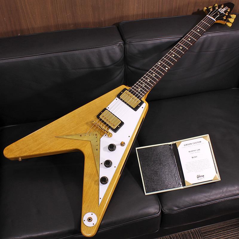 ■商品紹介ギターファン垂涎の生産僅少モデルCustom Shop Korina 1958 Flying Vの、さらにレアなMuphy LabによるAgedバージョンが入荷！リアルなMurphy Lab Light Agedにより一層雰囲気を高めた逸品です！お見逃しなく！！〜 Murphy Lab 〜カスタムショップ内に誕生したMurphy Lab（マーフィー・ラボ）は、ナッシュヴィルのギブソン・カスタムショップ内に新設されたラボで、科学的検証に基づく最新の技術を駆使して、ギターのエイジング（ヴィンテージ・ギターの経時変化した外観と弾き心地を再現する処理）を専門に行います。ギブソン・カスタムショップの立ち上げ時のメンバーであり、ヒストリック・コレクション開発のプロジェクト・リーダーとして尽力したトム・マーフィーは、その後新品のギターにヴィンテージのルックスとフィーリングをもたらすエイジングというテクニックで活躍してきました。トムのヴィンテージ・ギターへの情熱と深い知識に裏打ちされた技術によって、ギブソン・ギターの自然なラッカーのクラック、演奏による摩耗を見事に再現しています。トム・マーフィーとギブソンは、経時変化によりウェザーチェックと呼ばれるクラックを生じさせる、1950年代、1960年代のニトロセルロースラッカーを科学的に解析し、その変化のプロセスをひも解き、あらゆるモデルのプロトタイプによるテストを重ねて、ヴィンテージ同様のナチュラル・ウェザーチェックを再現するラッカー・プロセスを開発しました。マーフィー・ラボは、トム・マーフィーがギブソン・カスタムショップのチームを率いて、プロトタイプをもとに、あらゆるボディシェイプ、フィニッシュ、エイジング・レベルの検証を始めたことから、その構想が生まれました。その結果、これまでにないリアリティとこだわりを追求したエイジングを行うために、ギブソン・カスタムショップ内に設立されました。トム・マーフィーの存在と、その芸術的な作品の数々は、ギブソンの歴史の中で重要な役割を果たし、今もそしてこれからもマーフィー・ラボとして永遠に引き継がれていきます。本機は4段階で設けられたエイジングレベルの2番目となる「Light Aged」が施された1958 Korina Flying Vです。軽量なコリーナ材ならではの軽やかで澄んだ鳴り、58モデルだからこその厚みのあるボディとネックグリップにより生まれるファットで野性味のあるドライブ感満載のサウンドは唯一無二の魅力を持っています。Light Agedは軽度の凹みや塗装剥がれ等のダメージ、リアルな塗装の色艶とウェザーチェックを表現。指板エッジにはロールド加工が施され、優れたグリップ感がプレイヤーの皆様にはさらに嬉しい仕上げとなっております。ピックアップはCustombucker Alnico 3を搭載し、Korina Vらしい軽妙ながらも心地良い粘りが絶品クランチトーンを生み出します。程好くミドルが抜けたドライなサウンドはハードエッジに歪ませてもシャープな輪郭でトーンをキリっと引き締め、バンドアンサンブルの中でもしっかりとギターの抜け感を確保しながら周囲との馴染みも抜群です。滅多に出ないエイジドフィニッシュの1958 Korina Fring Vです！ぜひ貴方の大切なコレクションにお加え下さい！Serial No. 8 5741Weight≒3.36kg専用ハードケース、認書等付属■仕様詳細Body: Korina 2-PieceNeck: Korina / 1958 Flying V ProfileFingerboard: Indian RosewoodFrets: 22 / ReissuePickups: Custombucker Alnico 3Controls: 2 Volume 、Master Tone 、3-Way PU SelectorBridge / Tailpiece: ABR-1 / String through Body - Lacquered Brass ChevronTuners: Kluson Single RingHard ware: Murphy Lab Light Aged Gold検索キーワード：イケベカテゴリ_エレキギター_Vタイプ_Gibson_Custom Shop_新品 SW_Gibson_新品 JAN:4570156015778 登録日:2026/03/23 エレキギター ギブソン カスタムショップ
