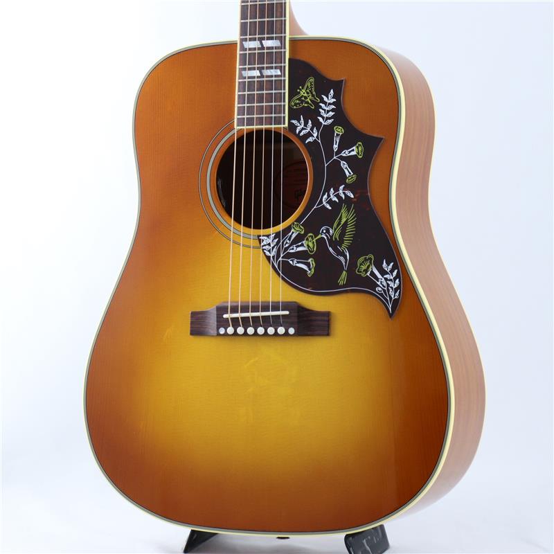 ■商品紹介長いアコースティックギターの歴史で老舗と呼ばれるメーカーの一つ「Gibson」。アコースティックギター界に多くの定番モデルを生み出しております。Gibsonアコースティックの人気機種で60年代に登場したハミングバードは、年式によって微妙にスペックの遍歴が有りますが、近年のモデルではウッドマテリアルにシトカ・スプルーストップ、マホガニーサイド＆バック、マホガニーネック、ローズウッド指板＆ブリッジと往年のスタイルを持ちつつ、握り易いネックグリップやピックアップの搭載等の扱い易さを併せ持った、伝統のスタイルを継承しながらも現代に合わせた仕様になっており、正に今のギブソンのスタンダードを感じられます。フルサイズのマホガニー・ボディと厳選されたシトカスプルース・トップの組み合わせから生まれる甘く極上のトーンは、バンドサウンドに埋もれない切れ味の良いカッティングから、フィンガーピッカーが求める繊細なピッキングニュアンスまでをもカバーします。カッタウェイ仕様によりハイフレット・ポジションでの演奏性が向上し、リード・プレイヤーを含め、より広い音域と表現力を必要とするプレイヤーに最適なハミングバードとして製作されており、これまで以上に多用途で表現力豊かなハミングバードです。TUSQ製ナット・サドル・ブリッジピン、モデル名のハチドリの意匠が施されたピックガードが装着されています。ピックアップシステムにはL.R.Baggs社製のピエゾピックアップ「Element VTC」を搭載、サウンドホールリムに取り付けられたボリュームとトーンコントロールで素早い調節が可能です。トラディショナルなハミングバードを継承しつつ、現代的な演奏性や使い勝手の向上をした。万能にオススメ出来る1本です。■仕様詳細Top：Sitka spruceBack：MahoganySide：MahoganyBracing：Traditional hand scalloped X-bracingBinding：Multi-ply top， multi-ply backFinish：NitrocelluloseNeckMaterial：MahoganyProfile：RoundScale Length：24.75 / 628.65mmFingerboard Material：RosewoodFingerboard Radius：12Number Of Frets：20Frets：StandardNut Material：BoneNut Width：1.72 / 43.81mmInlays：Mother-of-pearl ParallelogramsJoint：Compound Dovetail Neck-to-bodyHardwareTuner Plating：GoldBridge：Traditional belly upSaddle Material：BoneTuning Machines：Gotoh KeystonePickguard：.060'' HummingbirdTruss Rod Cover：HummingbirdBridge Pins：TusqElectronicsUnder Saddle Pickup：LR Baggs VTCControls：Volume and Tone controlsハードケース付属検索キーワード：イケベカテゴリ_アコースティック・エレアコギター_エレアコギター_Gibson_Square Shoulder_新品 SW_Gibson_新品 JAN:4580568415745 登録日:2026/07/26 エレアコ ギブソン ぎぶそん