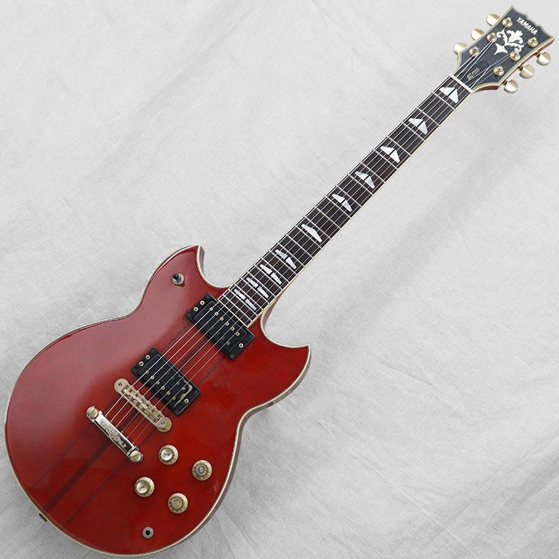 楽器種別：ヴィンテージYAMAHA/SG Series 商品一覧＞＞YAMAHA/ユーズド 商品一覧＞＞エレキギター【125，000円〜235，000円】 商品一覧＞＞SGタイプ/YAMAHA 商品一覧＞＞当店のギターは、出荷前に専門スタッフが検品・調整しているので安心です！YAMAHA VINTAGE SG-1500 '83 Persimmon Red商品説明1960年代に登場したヤマハオリジナルモデル「SG」シリーズ。古くはGS期に始まり、幾度かの大規模モデルチェンジを経て、1973年頃のSG-30／35からダブルカッタウェイシェイプに至ります。翌1974年のSG-175から現在まで続く伝統のSGシェイプが完成し、多数のバリエーションモデルを輩出してきました。今回入荷はシリアルナンバーから198年頃の出荷と見られる「SG-1500」、生産年数の短いレアモデルですね。【ボディ】全体重量約4.4kg。ボディカラーはヤマハ定番のパーシモンレッド、ゴールドハードウェアやシースルーカラーならではの木目感が非常にリッチな印象のルックスです。マテリアルはトップにメイプル、バックにマホガニー、スルーネック仕様となります。全体的に傷や打痕、金属パーツのくすみ、この時期のヤマハに多い塗装の白濁がございます。【ネック】前述のとおりスルーネック仕様、メイプル／マホガニーの3ピース。指板はローズウッドとなります。SG-2000に採用されるTクロスメイプルではなく一般的なスルーネックの仕様であることが外観からもピースが見て取れます。チューナーは巻き具合に若干のバラつきがありますがしっかりと機能しています。フレット／ナットは消耗が見られローフレットを中心にへこみがございますが、現状で極端なビビりや詰まりはなく演奏性は良好です。ナット幅約42.9mm。しっかりめの幅と薄めのネックシェイプが特徴です。【電装系】コントロールは【2ヴォリューム／2トーン／3wayピックアップセレクタースイッチ】に、各トーンPOTには伝統のバイサウンドスイッチを搭載。ピックアップはオリジナルのセミオープンタイプハムバッカーが2基。バイサウンドスイッチとSGピックアップの組み合わせで、厚みのあるハムバッカーからシャープなシングルコイルトーンまでカバー。無骨さと器用さを兼ね備えた良品ですね。付属品：YAMAHAハードケース商品詳細Weight：4.4kgBody Material（Top／Back）：Maple／MahoganyNeck Material：Maple／Mahogany， Through NeckFingerboard： RosewoodNut Width：42.9mmFret Width：2.8mmNeck Thickness（1F／7F／12F）：20.8mm／22.1mm／22.9mmPickup（Neck／Bridge）：YAMAHA Semi Open Humbucker（7.1kΩ／7.1kΩ）※ピックアップの直流抵抗値はコントロール部を通しての計測となります-------Heartman Vintage Guitarsは池部楽器店のヴィンテージ・ギター＆ベースの専門店です-------イケベカテゴリ_エレキギター_SGタイプ_YAMAHA_SG Series_ユーズド SW_YAMAHA_ユーズド JAN:2500010796941 登録日:2025/12/21 エレキギター ヤマハ やまは