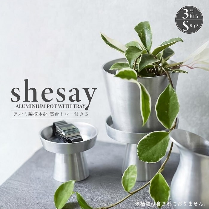 ■ 商品情報 ■ 植物を美しく引き立て、空間に立体感を加えるアルミで作られた「高台トレー付き植木鉢」Sサイズ。 軽く錆びにくいアルミニウム、シャープな素材感で陶器鉢では出せない無機質なカッコ良さを演出してくれる。玄関やデスク、リビングなど、場所を選ばずに飾れる丁度良いサイズ感。日常をさり気なくオシャレに演出。 高台付きトレーはアクセサリーや小物を置くこともでき、ディスプレイ什器として活用するのもオススメ。内寸で直径93mmと花苗で使用されるような標準的な「3号サイズ」のポットとなります。 1点1点手作業で溶接研磨し、鉢状に加工したシンプルながらも素材感が際立つ仕上り。表面を細かく研磨され使い込むほどにビンテージ感が程良く変化していく、素材の持ち味をお楽しみ下さい。 （※植物は附属しておりません。） （※本ページはSサイズとなります。） ■ 商品仕様／ SPEC ■ 品　名 shesay アルミ製植木鉢 高台トレー付属 Sサイズ サイズ セット時(約):Φ97×H140 mm / 内寸(約):Φ93 mm ポット(約):Φ97-Φ70×H85 mm / トレー(約):Φ92-Φ60×70 mm 素　材 アルミ 生産国 インド 備　考 ・底穴あり( Φ11 mm ) ・3号鉢相当 ・個箱入り ※ 特記事項 ※ ●ハンドメイド製品の風合いを活かした商品のため、刻印のムラや製造工程上のスレや小傷があります。予めご了承ください。 ●ご使用状況によっては風合いが褪せてきたり変色する場合がありますが、素材の持ち味としてご理解ください。◆ アルミ製植木鉢＆鉢カバーシリーズ ◆ ■ shesay アルミ製植木鉢 高台トレー付属 Sサイズ ■ ■ 商品仕様／SPEC ■ 品　名 shesay アルミ製植木鉢 高台トレー付属 Sサイズ サイズ セット時(約):Φ97×H140 mm / 内寸(約):Φ93 mm ポット(約):Φ97-Φ70×H85 mm / トレー(約):Φ92-Φ60×70 mm 素　材 アルミ 生産国 インド 備　考 ・底穴あり( Φ11 mm ) ・3号鉢相当 ・個箱入り ※ 特記事項 ※ ●ハンドメイド製品の風合いを活かした商品のため、刻印のムラや製造工程上のスレや小傷があります。予めご了承ください。 ●ご使用状況によっては風合いが褪せてきたり変色する場合がありますが、素材の持ち味としてご理解ください。