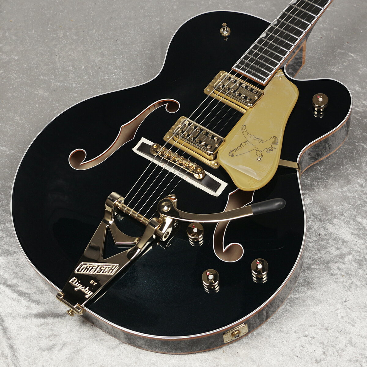 G6136TG Players Edition FalconTM Hollow Body with String-Thru Bigsby and Gold Hardware G6136TG Players Edition FalconTM Hollow Body with String-Thru Bigsby and Gold Hardwareは、歴史上最も望まれてい るギターの一つです。クラシックな外観から、深く繊細なサウンドまで、こ の優雅なギターは、自分の音楽をワンランク上の次元で奏でたいと望んで いるプレイヤーに理想的なモデルです。 新開発のFT-67 Filter’TronTMハムバッカーは、Gretschの正統なヴィン テージヴォイシングを再現しながらも、現代の演奏スタイルに合わせて幅 広いトーンが得られるように設計されています。このパワフルな2基のピッ クアップは、オープンでピュアなトップエンド、艶やかなミッドレンジ、力強 いローエンド、バランスの取れたハーモニクスを提供し、他の楽器とシー ムレスに調和するトーンを実現します。Gretschの革新的な”ML”ブレイ シングは、2.5インチ厚のメイプルボディからスケール感のあるホローボ ディサウンドを生み出します。また、ブリッジ/ネックピックアップの独立し たボリュームコントロール、3ウェイピックアップトグルスイッチ、No-Load マスタートーンとマスターボリュームというコントロールにより、無限のト ーンバリエーションを実現します。滑らかなヴィンテージトーンを実現す る”Squeezebox”コンデンサーや、ボリュームを下げてもサウンドの明瞭 度を損なわない新開発のトレブルブリード回路を搭載しています。 25.5インチスケールのメイプルネックには、ロールオフ処理を施した12インチラジアスのエボニー指板と22本のミディアムジャンボフレットを配し、 スタンダードな”U”ネックシェイプを採用することで、スムーズな演奏を可 能にします。Bigsby B6GPビブラートテールピースとAdjusto-MaticTM ブリッジに加え、Graph Tech TUSQ XLナットを採用することで、チュ ーニングの安定性を高めています。Bigsbyテイルピースはストリングスル ー構造になっており、弦交換が素早くできるようになった他、振動の伝達 性が高まり、サスティンが向上します。 Midnight Sapphire、もしくはWhiteグロスウレタンフィニッシュ、ゴール ドのGrover ImperialTMロッキングチューナー、ゴールドのGアローコン トロールノブ、ゴールドスパークルバインディングのネック、ボディ、Fホー ル、印象的なパーロイドNeo-ClassicTMサムネイルインレイ、Gretschと Falconのロゴが入ったゴールドヴィンテージプレキシピックガードなど、 パワフルなサウンドとステージでの柔軟性を誇る本モデルは、「洗練」とい う言葉を具現化した逸品です。 ■付属品：ハードケース、メーカー保証書※画像はサンプルです。 主な仕様 ■Neck ヘッドストックバインディング ネック：Maple ネックフィニッシュ：Gloss ネックシェイプ：Standard "U" ネック：Set-Neck フィンガーボードラジアス：12" (305 mm) FINGERBOARD MATERIAL：Ebony ポジションインレイ：Pearloid Neo-Classic Thumbnail フレット数：22 ナット：Graph Tech TUSQ XL ナット幅：1.6875" (42.86 mm) ナットの素材：Graph Tech TUSQ XL フレットサイズ：Medium Jumbo スケール：25.5" (64.77 cm) ■ボディ ボディ：Laminated Maple ボディフィニッシュ：Gloss ボディシェイプ：Falcon ボディトップ：Arched Laminated Maple ボディバインディング：Gold Sparkle with W/B/W/B Purfling ボディバック：Arched Laminated Maple BODY STYLE：Gretsch Hollow Body Guitars ボディ素材：Laminated Maple CUTAWAY：Single Cutaway ブレイシング：ML Bracing ウェイスト：10.375" (263.52 mm) SOUND HOLE：F-Holes, Bound ■Hardware ブリッジ：Adjusto-Matic with Pinned Ebony Base ブリッジカバー/テイルピース：Bigsby B6GP String-Thru BRIDGE MOUNTING：Pinned ピックガード：Gold Plexi with Gold Gretsch Logo and Black Falcon Graphic PICKUP COVERS：Gold コントロールノブ：Jeweled G-Arrow ハードウェアフィニッシュ：Gold チューニングマシーン：Grover Imperial Locking ストリング：Nickel Plated Steel (.011-.049 Gauges) STRAP BUTTONS：Grover Strap Locks ■Electronics ブリッジピックアップ：FT-67 Filter’Tron ネックピックアップ：FT-67 Filter’Tron コントロール：Volume 1. (Neck Pickup), Volume 2. (Bridge Pickup), Master Volume w/ Treble Bleed, Master Tone w/ No-Load Pot SWITCHING：3-Position Toggle: Position 1. Bridge, Position 2. Bridge and Neck, Position 3. Neck