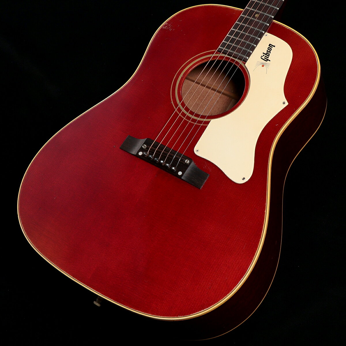 1968年製、Gibson J-45 Adjustable Cherry Redが入荷しました。 60年代の後半にカスタムカラーとしてエボニーブラックとチェリーレッドカラーが極少数本のみ生産。当時でもカスタムオーダーカラーとして手に入るカラーリングであった為に、なかなか手に入れられる仕様では無いと言えるのではないでしょうか。50年代にも代表的なラージピックガードも60年代半ばから厚みのあるピックガードに変更され、かの有名なGibson ロゴが入れられている個体も存在。本器はそのGibsonロゴ入りホワイトラージピックガードが採用されている個体となります。アッパーベリーブリッジ、ウッドサドルのアジャスタブルサドルが放つ、豪快かつバランスの良い軽快なサウンドも程良いドンシャリ感に仕上がっており、約40mmナット幅のナローネックも相まってコードストロークでのプレイを存分にお楽しみいただけるサウンドに仕上がっております。 カラーリングも通常であれば色焼けにより茶色に近い状態に経年変化していきますが、本器は当時のチェリーレッドカラーをしっかりとご堪能いただけるほどにコンディションが保たれております。プレイコンディションもしっかりと保持されており、ペグの交換やブリッジの再接着、ネックリセットが行われトラスロッドも調整可能な状態です。ボディセンターにはボディ内部よりブリッジ〜ボディエンドにかけてパッチ修正が行われており、ブリッジ付近6弦側、6弦側バインディング付近(くびれ付近)に割れが確認されますが、こちらは木部まで到達しておらず塗装割れとなっており、ブレーシング箇所である事から問題ございません。 また、6弦側ショルダーに木が露出する塗装剥がれ(塗装焼けと思われる)があり、剥がれが広がらない様タッチアップにて固められている形跡があります。 60年後半のカラーリングJ-45のヴィンテージでは、色やけや経年変化によるパーツ交換、木部の修復などが多く行われている個体が多いですが、本器は非常に良いコンディションを保っている為、これからも更に弾き込んでより良いサウンドとルックスに自身の手で仕上げていける余力を残している一本です。 大変稀少かつ価格の高騰が激しいヴィンテージ45、このチェリーレッドをお探しの方も多いのではないでしょうか。大変人気な機種である為、気になっている方はお早目にどうぞ。 ※非純正ハードケース付属 ■商品ランク:B：かなり、傷&使用感はあるが、通常使用する用途において問題なし ■製造年:1968 ■保証:12ヶ月 ■シリアルナンバー:905135 ■ケース:ハードケース/非純正 ■重量:- kg ■フレット残り:70%〜80%程度 ■トラスロッド:締め/緩め方向に余裕あり ■ネックコンディション:問題無し ■説明書:なし ■他付属品:なし ■備考：その他付属品は画像に写っているもののみとなります。 ----------------------------- ▼必ずお読み下さい ※こちらの商品は中古品の現物1点限りでございます。 ※中古品につき、使用による傷・打痕等、写真に写りにくい傷がございます。予めご了承くださいませ。 ※店頭及び、複数のモールに掲載されているため、販売状況・在庫状況にはタイムラグがあり、リアルタイムではございません。 その為、ご注文時に既に売却済となっている可能性がございます。