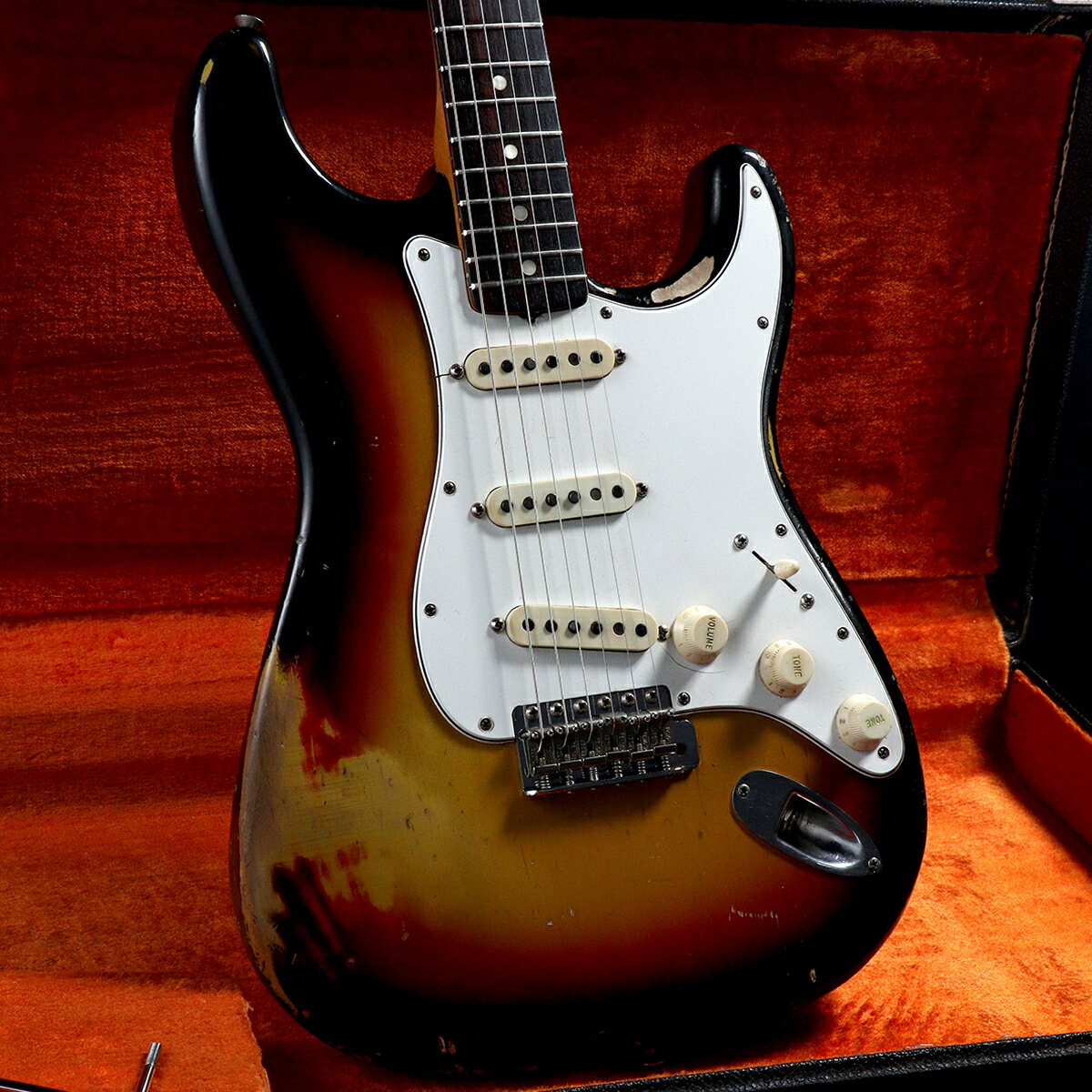 1966年製、Fender Stratocasterが入荷！！1965年にCBS（コロンビア・レコード）に買収され、そうした背景の中、生産体制も変わり、デザインにも少し変化が生じることになった年代の本機。特徴としてはヘッド形状が、それ以前のモデルに比べて、サイズが大きくなり、厚みも増し、外周ラインまでも変わっています。ナットから6弦のストリング・ポストまでの距離が1965年までのモデルと比べて異なっており、この外形上の変化により弦のテンションバランスも変わったこともあげられます。本機はシリアル189422、Neck Dateは13APR66Bの1966年製となります。ボディ材はアルダー。退色により2Tone気味になる個体もある中、本機は赤みをある程度しっかり残しております。PGに割れ、木部のウェザーチェックやコンター付近の塗装剥がれ、ベルトバックルや木剥がれ、パーツのくすみ等が見られますがヴィンテージギターらしい素晴らしい雰囲気を醸し出しております。ネックは13APR66BのBネック。ネック材はメイプル、指板材はローズウッドです。ネック裏のラッカーは使用により剥げておりますが、ヴィンテージ特有の滑らかな手触りとなっており、プレイ面での不安はございません。ペグはオリジナルのクルーソンデラックスを搭載しており、巻きの締め具合にばらつきはありますが良好に動作しています。ヘッド表にはテンションピンを追加した跡がございますがキレイに修正されています。ピックアップは66年デイトのグレイボビン×3。オリジナルではございますがリード線を追加した形跡がございます。Volume Potは交換、Tone PotはTone1（304-6532）、Tone2（304-6610）のオリジナルとなっています。その他、ピックアップセレクター、アウトプットジャックも交換済みです。近年、価格高騰が止まらないヴィンテージギター、ぜひこの機会にご検討くださいませ。コンディションは、全体的に打痕やキズ、塗装剥げ等ございますが、年式を考慮すれば、特に気にならないと思われます。フレットもしっかり残っており、プレイアビリティも良く、これからも十分お使いいただける個体でございます。※こちらの商品は現物1点限りを、店頭展示を含め複数のモールに同時掲載しております。売却に伴う商品情報の削除は迅速を心掛けておりますが、必ずしもリアルタイムではございません。ご注文後に万一売り切れとなっておりました際は、誠に申し訳ございませんがご容赦くださいませ。 製品仕様 商品ランクB+：多少傷はあるが通常使用する用途において問題なし製造国アメリカ製造年1966保証12ヶ月シリアルナンバー189422ケースハードケース/純正重量3.64kgフレット残り70&#37;〜80&#37;程度トラスロッド締め/緩め方向に余裕ありネックコンディション良好説明書なし他付属品アーム備考その他付属品は画像に写っているもののみとなります。