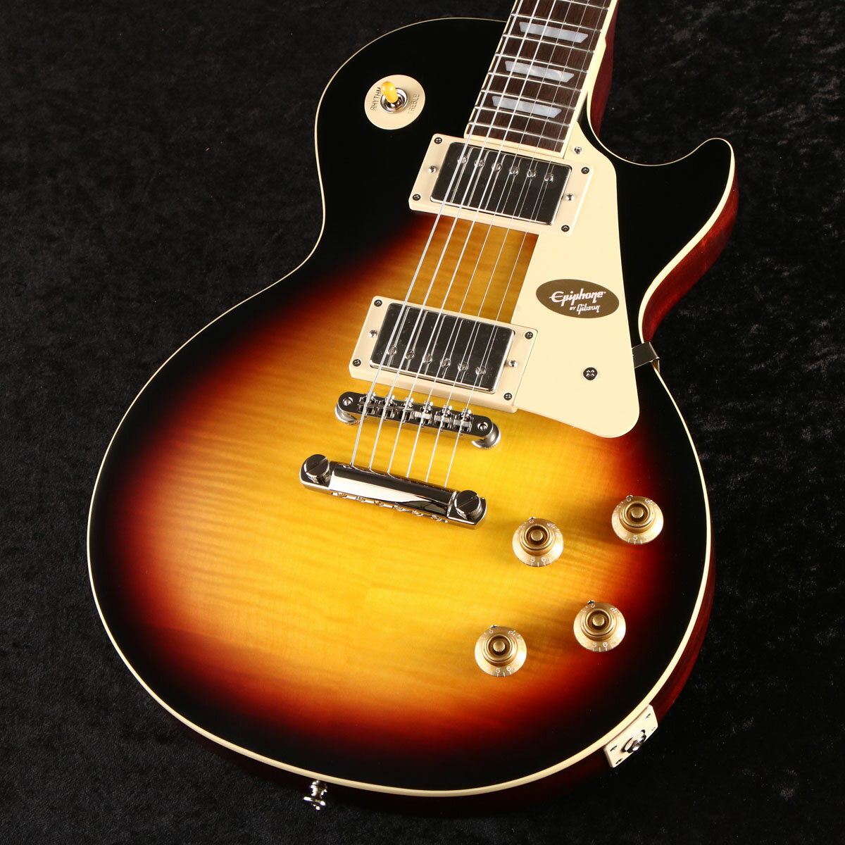 Epiphone Inspired by Gibson Custom Shopから1959 Les Paul Standardがリリース！ EpiphoneとGibson Custom Shopのコラボレーションによって製作されるEpiphone Inspired by Gibson Custom Shopのラインナップが大幅に刷新されました。 既にリリースされている1958 Korina Flying V/Explorer、1963 Firebird I/Vに加えて、 今回Les Paul Standard、SG Custom、ES-355、Les Paul CustomといったGibsonを代表するモデル群が新たにリリースされます。 エピフォンはギブソン・カスタム・ショップとのコラボレーションにより、希少なヴィンテージクラシックを見事に再現した1959 Les Paul Standardをリリースします。 1959 Les Paul Standardは、マホガニーBodyにAAAフレイム・メイプル・ベニアのメイプルTop、1959スタイルを踏襲した丸みを帯びたミディアムCプロファイルの1ピース・マホガニー・ネック、ジョイントはロング・ネック・テノン（ディープジョイント）を採用。 ヘッドストックはGibsonオリジナルの“openbook”ヘッドストック・シェイプが採用され、エイジドMOPロゴ、チューナーやピックガード、バインディングもヴィンテージスタイルが再現されています。 ピックアップにはCustom Shop製品にも採用されているGibson Custombuckerをマウント。 さらに50sワイヤリング、CTSポテンショメーター、Malloryコンデンサー、Switchcraftセレクタースイッチとアウトプットジャック、も採用され、サウンド面においても充実のスペックを誇ります。 ヴィンテージスタイルのInspired by Gibson Customロゴ入りのハードシェル・ケースが付属いたします。 エピフォンとギブソン・カスタム・ショップのコラボレーションは、紛れもなく、親しみやすく、高品質なギターを生み出し続けています。 真正性、ルックス、トーン、フィーリングをさらに高めた新しいEpiphone Inspired by Gibson Custom 1959 Les Paul Standard はたゆまぬ探求における数十年の努力の集大成でもあります。 ■付属品：ハードケース、ユーザー登録カード ※ご購入後、同梱されるユーザー登録カードに必要事項をご記入の上、15日以内にギブソン・ジャパンへご郵送ください。ユーザー登録したご本人様に限り、メーカー規定の故障に対して保証が提供されます。 主な仕様 Shape | Les Paul Material | Mahogany Top | Maple with AAA Flame Maple Veneer Finish | VOS Vintage Original Sheen Weight Relief | N/A Binding | Single Ply, Top and Fretboard Neck | One Piece Mahogany Neck Profile | 1959 Rounded Medium C Nut width | 43mm Fingerboard | Laurel Scale length | 628.65mm Number of frets | 22 Nut | Graph Tech Inlay | Mother of Pearl Trapezoid Bridge | ABR-1 Tailpiece | Gibson Historic Reissue Stop Bar Tuners | Epiphone Deluxe with Keystone Buttons Plating | Nickel Neck pickup | Gibson Custombucker Bridge pickup | Gibson Custombucker JAN 4570156001764 個体情報 シリアルナンバー　23121521640 重量　3.72kg 製品仕様 Shape Les PaulMaterial MahoganyTop Maple with AAA Flame Maple VeneerFinish VOS Vintage Original SheenWeight Relief N/ABinding Single Ply, Top and FretboardNeck One Piece MahoganyNeck Profile 1959 Rounded Medium CNut width 43mmFingerboard LaurelScale length 628.65mmNumber of frets 22Nut Graph TechInlay Mother of Pearl TrapezoidBridge ABR-1Tailpiece Gibson Historic Reissue Stop BarTuners Epiphone Deluxe with Keystone ButtonsPlating NickelNeck pickup Gibson CustombuckerBridge pickup Gibson CustombuckerControls 2 Volume, 2 Tone; CTS Potentiometers and Mallory Capacitors, 50s WiringCase Brown Hardshell with Pink Interior, Gold Hardware, and Inspired by Gibson Custom Logo