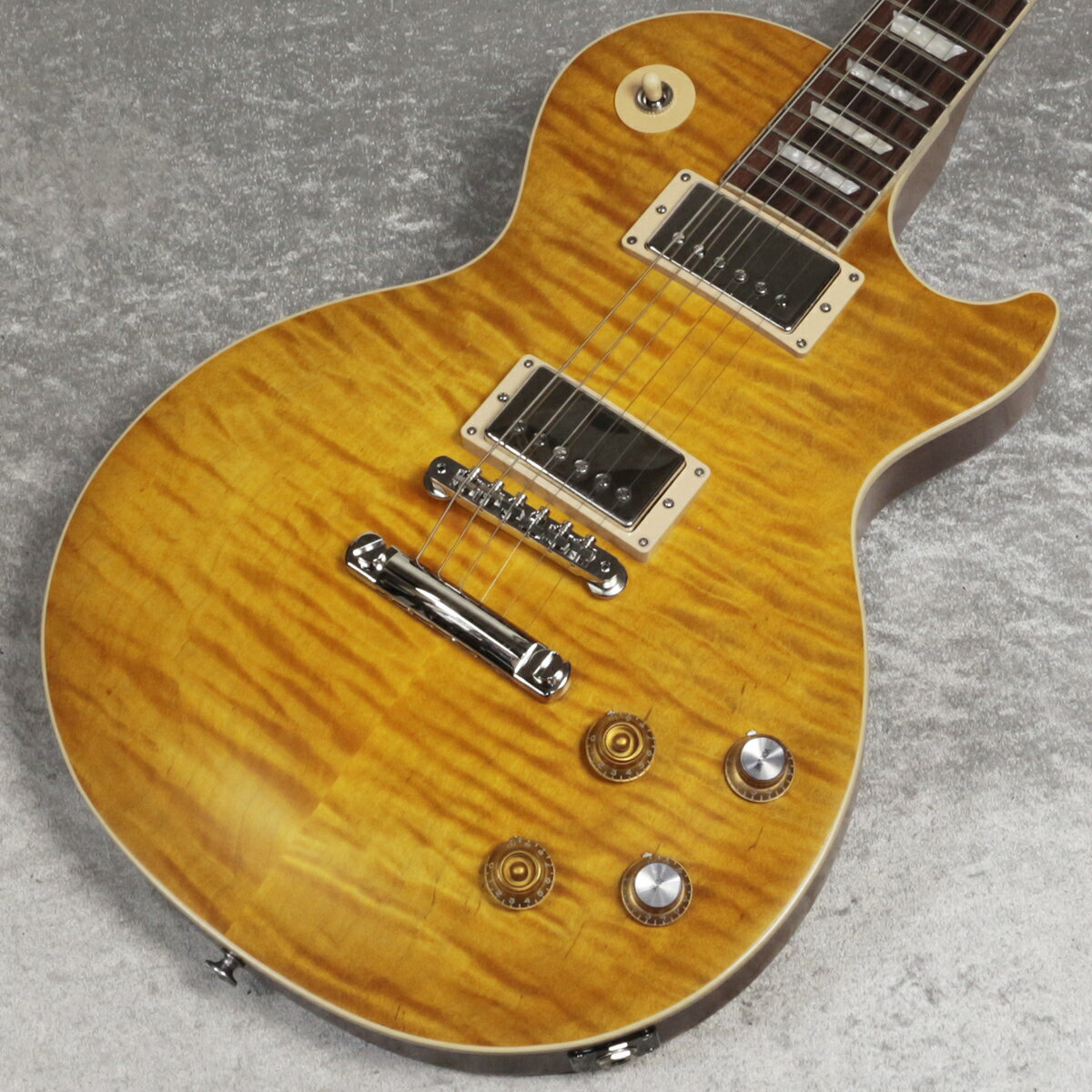 あの伝説的なギターを再現！カーク・ハメット“Greeny”レス・ポール・スタンダード！ 多くのギタリスト、Gibsonファンが一度は目にしたことがあるであろう、これまで3人のレジェンド・ギタリストに"弾き"継がれたレス・ポール・スタンダード。 ピーター・グリーン、ゲイリー・ムーア、カーク・ハメットのファンは勿論のこと、かつてGibson Custom ShopのCollector's Choiceとして製作されたのも記憶に新しいです。 USAレギュラーモデルとして生産される本モデルは、リアピックアップ付近のダメージやピックガードのビス穴など所謂Aged加工はされていないものの、AAAフィギュアド・メイプルTopや、Greenybuckerピックアップを採用し、さらにリフレクターノブやネックピックアップのマグネット反転まで再現しております。 しっかりとした握り心地の50s Vintageプロファイルネック、センターポジションでの独特で魅力的なサウンドで、憧れの“Greeny”を体感することができます。 Made in USA、新品、正規輸入品です。 “Greeny”のストーリーは非常にミステリアルですが、これほどまでに輝かしいストーリーを持つギターはそうありません。 “Greeny”は、これまでに作られたオリジナル・シリーズのレスポール・スタンダードの中で最も象徴的な1本で、ギターの知名度と並び、実にユニークなサウンドも特徴です。 以前はピーター・グリーン（フリートウッド・マック）が所有しており、その後ゲイリー・ムーアに売却され、シン・リジィとソロ・アーティストとして30年間使用されました。 現在はカーク・ハメットが所有しており、”Greeny”は3人の伝説のギタリストの手に渡り、プレイされ続けているのです。 その特徴的なサウンドは、ネックピックアップのマグネットを反転させているため、トグル・スイッチをセンター・ポジションにした際に奏でるそのフェイズ・サウンドに起因しています。 Kirk Hammett "Greeny" Les Paul Standardは、この伝説的なギターにインスパイアされ、世界中のプレイヤーに“Greeny”マジックを体験してもらう機会を提供するものです。 オリジナル・シリーズのハードシェル・ケースが付属します。 主な仕様 Body Shape : Les Paul Body Material : Mahogany Top : AAA Figured Maple Binding : Single Ply Cream, Top and Fretboard Body Finish : Satin Nitrocellulose Lacquer Neck : Mahogany Neck Profile : 50s Vintage Nut width : 1.695" / 43.053mm Fingerboard : Indian Rosewood Scale length : 24.75" / 628.65mm Number of frets : 22 Nut : Graph Tech Inlay : Acrylic Trapezoid Bridge : ABR-1 Tune-O-Matic Tailpiece : Aluminum Stop Bar Knobs : Amber Top Hats and Gold Top Hats with Gold Reflector and Pointers Tuners : Grover Rotomatics with Contemporary Buttons Plating : Nickel Reverse Mounted Bridge pickup : Greenybucker Controls : 2 Volume, 2 Tone, Hand-wired with Orange Drop Capacitors ■重量 : 4.02 kg■JAN : 4580568432261 ■付属品：ハードケース、Gibsonユーザー登録カード ※ご購入後、同梱されるユーザー登録カードに必要事項をご記入の上、ギブソン・ジャパンへご郵送ください。 ユーザー登録したご本人様に限り、メーカー規定の故障に対して保証が提供されます。 複数のサイトに掲載しておりますため、他のサイトにて既にご販売済みである場合もございます。 売却に伴う商品情報の削除は迅速を心掛けておりますが、ご注文後に万一売り切れとなっておりました際は誠に申し訳ございませんがご容赦くださいませ。 S:新品