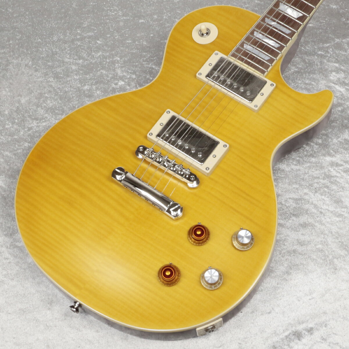 Epiphone Inspired by Gibson Custom Shopから、遂にあの"Greeny"がリリース！ Custom ShopからリリースされたKirk Hammett "Greeny" 1959 Les Paul Standard Murphy Lab Aged、USAからリリースされたKirk Hammett "Greeny" Les Paul Standardが記憶に新しいですが、ついにEpiphone(Inspired by Gibson Custom Shop)ブランドからもあの伝説的なレス・ポールを再現したモデルがリリース！ 今回リリースされたEpiphone Kirk Hammett "Greeny" 1959 Les Paul Standardは、エピフォンとギブソン・カスタム・ショップの緊密なコラボレーションにより開発されました。 カーク・ハメットが愛用している伝説的なオリジナル"Greeny"にインスパイアされ、オリジナル同様に特徴的なスペックを備えております。 USA製モデルと同じGibson USA Greenybuckerピックアップを搭載し、勿論ネックピックアップは反転されております。 ネックシェイプもCustom Greeny Profileを採用し、さらにリア側のリフレクターノブ、"Spade"ボタンGroverペグなどオリジナルを忠実に再現しております。 そして特筆すべきはヘッドストックシェイプです。遂にEpiphoneのコアモデルでもGibsonオリジナルの“openbook”ヘッドストックを採用されることとなり、Epiphone Kirk Hammett "Greeny" 1959 Les Paul Standardがその最初のモデルとなります。 その他にもGibson Custom Shopとのコラボレーションモデルに相応しく、Switchcraft製ピックアップ・セレクターとアウトプット・ジャック、CTS製ポテンショメーター、Mallory製コンデンサーなど、プレミアムなパーツを採用しています。 ルックスだけでなくサウンド、プレイフィールに於いても、あの伝説的ギター”Greeny”の"魔法"のような魅力を体験することができる、Epiphoneブランド最高峰に位置するモデルです。 EpiphoneとGibson Custom Shopのコラボーレションロゴの入ったヴィンテージスタイルのハードシェル・ケースが付属します。 ■付属品：ハードケース、Epiphoneユーザー登録カード ※ご購入後、同梱されるユーザー登録カードに必要事項をご記入の上、15日以内にギブソン・ジャパンへご郵送ください。ユーザー登録したご本人様に限り、メーカー規定の故障に対して保証が提供されます。 主な仕様 Body Shape | Les Paul Body Material | Mahogany Body Top | Maple with AAA Flame Maple Veneer Neck | One Piece Mahogany Profile | Custom Greeny Profile Nut width | 43mm Fingerboard | Indian Laurel Scale length | 628.65mm Number of frets | 22 Nut | Graph Tech Inlay | Mother of Pearl Trapezoid Bridge | Epiphone ABR Tailpiece | LockTone Stop Bar Tuners | Grover Rotomatic with Kidney Buttons Plating | Nickel Neck pickup | Gibson USA Greenybucker with Reversed Magnetic Polarity;Reverse Mounted Bridge pickup | Gibson USA Greenybucker Controls | 2Volume, 2Tone, 50s Wiring, CTS Potentiomenters, Mallory Capacitors Case | Vintage-style Hardshell with Tan Exterior, Pink Interior, and Custom Artwor JAN 4570155996528 個体情報 重量　3.85kg 製品仕様 Body Shape Les PaulBody Material MahoganyBody Top Maple with AAA Flame Maple VeneerNeck One Piece MahoganyProfile Custom Greeny ProfileNut width 43mmFingerboard Indian LaurelScale length 628.65mmNumber of frets 22Nut Graph TechInlay Mother of Pearl TrapezoidBridge Epiphone ABRTailpiece LockTone Stop BarTuners Grover Rotomatic with Kidney ButtonsPlating NickelNeck pickup Gibson USA Greenybucker with Reversed Magnetic Polarity;Reverse MountedBridge pickup Gibson USA GreenybuckerControls 2Volume, 2Tone, 50s Wiring, CTS Potentiomenters, Mallory CapacitorsCase Vintage-style Hardshell with Tan Exterior, Pink Interior, and Custom Artwork