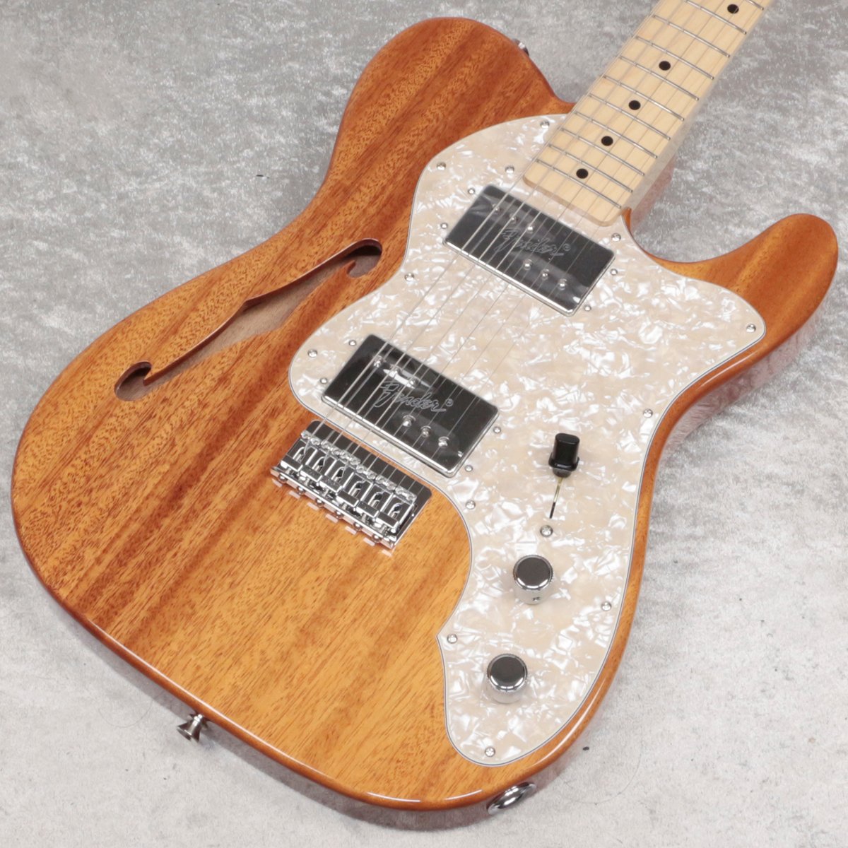 人気のテレキャスター・シンライン。なんとボディー材にマホガニー材を使用したモデルをイシバシ楽器独占販売！ かつてTN72 MAHOとしてFender JAPANより発売されて人気を博したモデルに近しいモデルとなっております。 基本スペックはTraditional IIシリーズの70s Telecaster(R) Thinline, Maple Fingerboard, Natural（UPC:885978483846)と同じとなっておりますが、 ボディー材をアッシュからマホガニーに変更。 マホガニー材をボディー材として採用する事で、より豊かな中域となり、セミホロウボディのシンラインとはサウンドの相性がバツグンです。 レギュラーでラインナップされてないのが不思議なくらいの王道な組み合わせです。 単音でも細くならないサウンドはマホガニーならでは、カッティング中心のバッキングサウンドはもちろんですが、ソロ弾きにも威力を発揮します。 ギター・ボーカルの方が持っているイメージが強いシンラインですが、是非純粋なギタリストの方にもおすすめしたい一本です。 歪ませたサウンドもGibson系ギターとFenderの中間の様な雰囲気があり、Marshallとの相性も抜群！ また、敢えてメイプル指板を採用する事で、柔らかいサウンドになりすぎず適度にパンチが聴いたサウンドとなり、バンド内での音抜けも良いモデルとなっております。 ピックアップにはFender Wide Range Humbuckingを2基搭載。ハムバッカーながら出力を低めに設定しており、ヴィンテージの 枯れたトーンやピッキングニュアンスが出やすいシンラインには欠かせない人気のピックアップです。 ネックは”U”シェイプでナット幅1.615" (41.02 mm)と日本人の手にも馴染みやすい細めのグリップを採用しております。 落ち着きのある見た目ですが深みのマホガニーブラウンは飽きの来ないルックス。ナチュラルフィニッシュなので一本一本木目が異なりますので 是非在庫がある内に、お気に入りの木目の個体を見つけてください。 完全限定、イシバシ独占販売となります。是非お早目にご検討下さい。 Body:Mahogany Neck:Maple Neck Finish:Gloss Urethane Neck Shape:"U" Shape Scale:25.5" Fingerboard:Maple Fingerboard Radius:9.5" Flet number:21 Flet Size:Vintage Nut:Bone Nut Size (mm):41 Position Inlay:Black Dots Pickups:Traditional Wide range humbucker(Bridge,Neck) Control:Master Volume, Master Tone Pickup Switch:3-Position Blade Bridge:6-Saddle Strings-Through-Body Hardtail Tuning Machine:F-Key Pickguard:3-Ply Aged White Pearloid Control Knob:Knurled Flat-Top Switch Tip:TOPHAT Black ■JANコード：0717669909185 ■重量：3.00kg ■付属品：ソフトケース、メーカー保証書