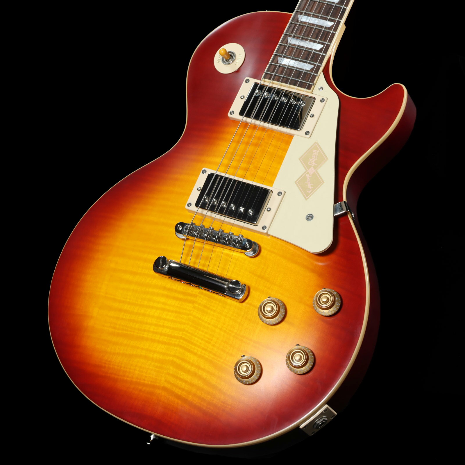 海外ディーラー向けに生産されたエクスクルーシヴモデル！ 人気のEpiphone Inspired by Gibson Customコレクションをベースに、Custom Shopカラーである"Sunrise Teaburst"を採用したエクスクルーシヴモデル！ EpiphoneとGibson Customの親密なリレーションによって実現した特別なレスポール・スタンダードです。 日本国内入荷数には限りがございますので、気になった方はお早めに！ 1959 Les Paul Standardは、マホガニーBodyにAAAフレイム・メイプル・ベニアのメイプルTop、1959スタイルを踏襲した丸みを帯びたミディアムCプロファイルの1ピース・マホガニー・ネック、ジョイントはロング・ネック・テノン（ディープジョイント）を採用。 ヘッドストックはGibsonオリジナルの“openbook”ヘッドストック・シェイプが採用され、エイジドMOPロゴ、チューナーやピックガード、バインディングもヴィンテージスタイルが再現されています。 ピックアップにはCustom Shop製品にも採用されているGibson Custombuckerをマウント。 さらに50sワイヤリング、CTSポテンショメーター、Malloryコンデンサー、Switchcraftセレクタースイッチとアウトプットジャック、も採用され、サウンド面においても充実のスペックを誇ります。 ヴィンテージスタイルのInspired by Gibson Customロゴ入りのハードシェル・ケースが付属いたします。 エピフォンとギブソン・カスタム・ショップのコラボレーションは、紛れもなく、親しみやすく、高品質なギターを生み出し続けています。 真正性、ルックス、トーン、フィーリングをさらに高めた新しいEpiphone Inspired by Gibson Custom 1959 Les Paul Standard はたゆまぬ探求における数十年の努力の集大成でもあります。■シリアル：25031525525■重量：3.70kg■付属品：ハードケース、正規保証 ※ご購入いただいたご本人様に限り、メーカー規定の故障に対して保証が提供されます。保証修理受付の際は「ご購入時の領収書もしくは納品書」をご提示いただきます。 製品仕様 ShapeLes PaulMaterialMahoganyTopMaple with AAA Flame Maple VeneerFinishVOS Vintage Original SheenWeight ReliefN/ABindingSingle Ply, Top and FretboardNeckOne Piece MahoganyNeck Profile1959 Rounded Medium CNut width43mmFingerboardLaurelScale length628.65mmNumber of frets22NutGraph TechInlayMother of Pearl TrapezoidBridgeABR-1TailpieceGibson Historic Reissue Stop BarTunersEpiphone Deluxe with Keystone ButtonsPlatingNickelNeck pickupGibson CustombuckerBridge pickupGibson CustombuckerControls2 Volume, 2 Tone; CTS Potentiometers and Mallory Capacitors, 50s WiringCaseBrown Hardshell with Pink Interior, Gold Hardware, and Inspired by Gibson Custom Logo