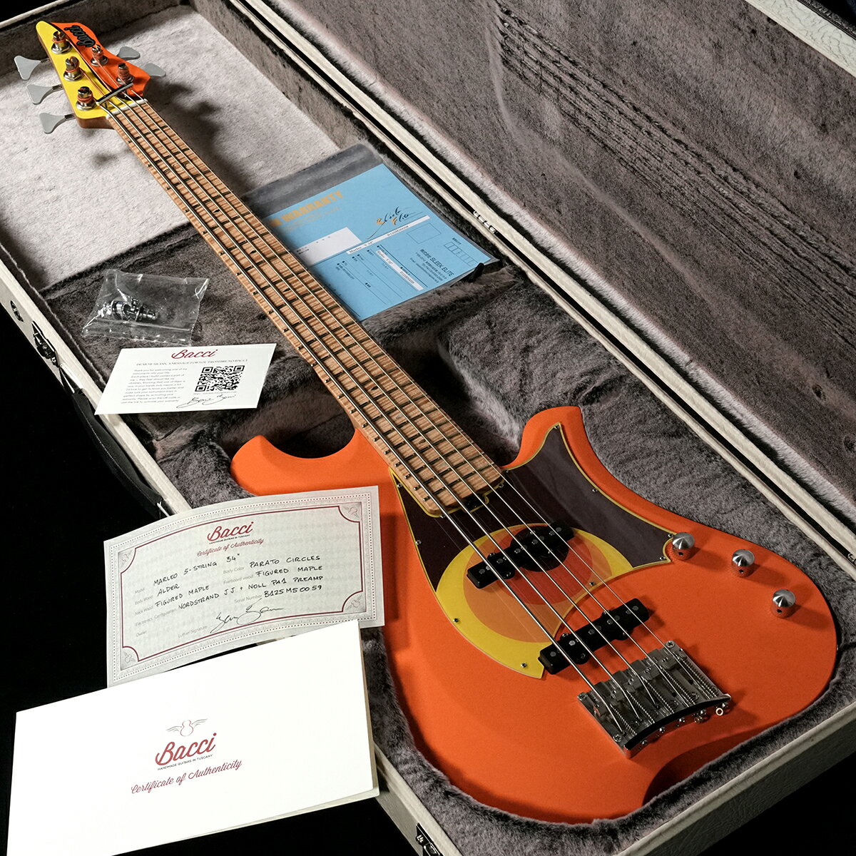 イタリアン・ハンドメイドブランド"Bacci"の『Marleo V 34inch』が入荷！Bruno Bacciはイタリア、トスカーナ出身のルシアーです。1975年生まれの彼は、 20代から30代にかけて冶金学からマーケティング、大工職、グラフィック デザインに至るまで、さまざまな分野でスキルを磨きました。この多様な背景は彼は弦楽器製作者としての仕事に独自の視点をもたらしています。近年の名プレーヤーとして名が上がるVincen GarciaやMichael League、Matteo Mancuso、Cory Wongといった錚々たる顔ぶれがBacciを使用していることでも知られているでしょう。イタリアンメイドならではの洒落たデザインに目にがいきますが、最終的に行き着くコメントとしては「とにかく楽器としての質がスバラシイ」です。良い楽器というのはこういうことですよね。というのがわかる品物です。ぜひお試しください。ボディーはAlder、指板・ネックはワンピースのFigured Mapleが柾目で取られています。こちらは4.40kgと適度な重量感で、独特のボディーデザインでバランスの良さがあり、演奏性含め全体のまとまり感が高いレベルで実現されています。ピックアップはNordstrand JJ。プリアンプにはNoll PA1を搭載。Noll PA1は積極的な音作りをするタイプのプリアンプではなく、バッファーアンプ的な役割です。弾いてみるとたしかにパッシブの質感ではないのですが、過剰にまとまりすぎる感じもなく、自然に持ち上げてくれてつかいやすいイメージです。TONEノブのPULLでBoostされ、キャビティー内のトリマーで15dBまでのBoost量の設定が可能です。ブリッジなどのハードウェアもオリジナルのパーツを採用。バックのテイルピースがおしゃれです。イタリアン。裏・表通しどちらにも対応しています。チューナーには定評があり信頼性の高いHipshotのUSA製が採用されているのもさすがのチョイスですサイドのポジションマークは蓄光素材(Green)。一般的に蓄光の周りには白か黒のリングをつかいますが、なんとGoldのリングでした。これもおしゃれポイントです。そしてノブのポインターもボディーカラーに合わせてオレンジになっています。たまりませんね。ハードケースもアンティークなルックスのオリジナルケースです。こちらもイカしてます。自信を持っておすすめ出来る良い楽器です。是非お試しください。※ハンドメイド製品のムラなどある箇所がございます。ご了承くださいませ。※こちらのお品物は渋谷店のみでの販売とさせて頂きます。■S/N:B12SMS0059■重量:4.40kg■JANコード:2100000950409■付属品:ハードケース、スペックシート、メーカー代理店保証書 製品仕様 Body AlderNeck&FB Figured MaplePickups Nordstrand JJPreamp Noll PA1Control 2Vol,1Tone&#40;boost&#41;