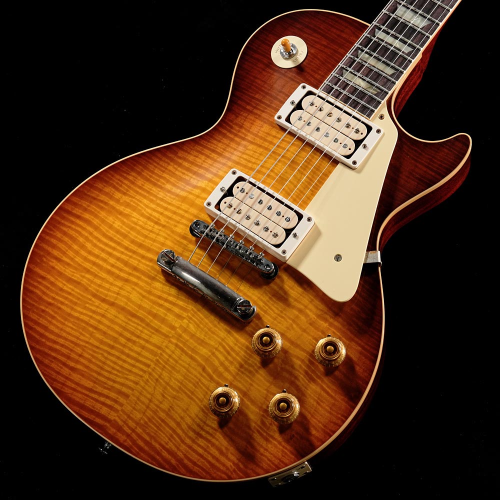 選定"R-Top"仕様！極上の1959 1959 Les Paul Standard入荷！Nashville Custom Shop Factory現地でハンドセレクトした、極上のトップ材を使用した一本です！！ギブソンの中でも最上位のRトップを採用し、Alnico 4マグネットを使用したCustombuckerを「Double Classic White」のオープンカバーにて搭載。1959 Les Paul Standard Reissueは、至高の存在である1959年製の完全なクローンとして、ヴィンテージをスキャンして得たデータ、素材成分の分析により再現されたレプリカ・パーツ、印象的なサンバーストのバリエーションの再現に至るまで、1993年以降、カスタムショップが蓄積してきた技術の粋を結集した最高の完成度となっています。ボディトップは材選定による Rトップ(5Aグレード・フィギュアドメイプル)、1ピース・マホガニー・バック、ネックにはソリッド・マホガニー、ローズウッド指板を使用。セットネックはディープジョイント（ロングテノン）、接着には膠（ハイドグルー）を使用。ハードウェアはKluson製 Single Line/Single Ring、ノンワイヤーのABR-1 Bridge、Lightweight Aluminum Stop Barを使用し、その他ヒストリックパーツを使用しております。ピックアップにはAlnico 4マグネットを使用したCustombuckerの「Double Classic White」を搭載。Alnico 3を使った通常のカスタムバッカーと比較して出力が高く、コシと粘りがあるパワフルさと、カバーレスによるブライトさが共存した、濃厚で芳醇なサウンドが非常に心地良いです。また、ルックスに於いてもダブルホワイトの持つ清涼感がとびきりのアクセントになっています。今回入荷の個体は重量もとにかくトップの見栄え抜群！重量も約3.8kgとまさに理想の59レスポールと言える極上の逸品です！■S/N:952213■重量:3.86kg■JANコード:4570156015938■付属品:ハードケース、ピックアップカバー、認定書、Gibsonユーザー登録カード※ご購入いただいたご本人様に限り、メーカー規定の故障に対して保証が提供されます。保証修理受付の際は「ご購入時の領収書もしくは納品書」をご提示いただきます。製品仕様Body Top : 2-Piece Hand Selected R-Top (5A Grade Figured Maple)Body Back : MahoganyNeck : MahoganyNeck Profile : Authentic 59 Medium C-ShapeFingerboard : Indian Rosewood, Hide Glue FitNut : NylonBridge : No-Wire ABR-1Tailpiece : Light Weight Aluminum Stop TailpieceTuning Keys : Kluson Single Line, Single RingRhythm Pickup : Custombucker Alnico IV (Unpotted)Lead Pickup : Custombucker Alnico IV Overwound (Unpotted)Controls : CTS 500K Audio Taper Potentiometers, Paper-in-Oil Capacitors