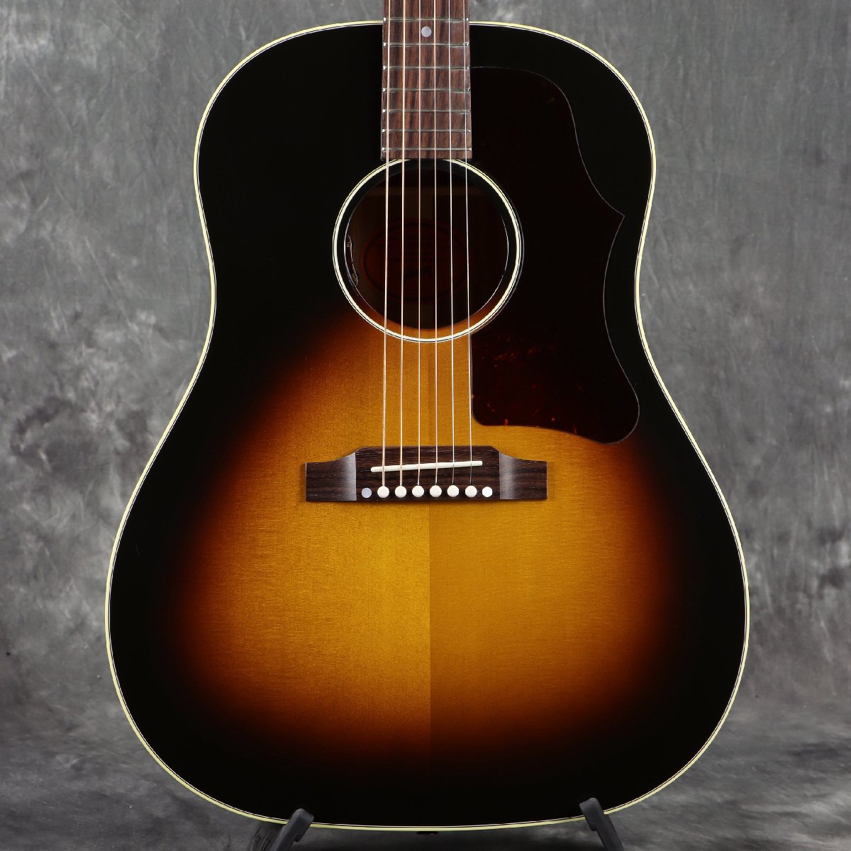 ■こちらの商品は実機画像を掲載しており、店頭未展示の倉庫保管品となります。出荷前に専任スタッフにより楽器の各部機能チェックを行っております。 人気の50sスタイルのJ-45！ J-35の後継機種として1942年に誕生した、ラウンドショルダー・アコースティックギターの「J-45」。 現在に至るまで多くのミュージシャン・ギタリストに愛され続けてきたモデルで、"The Workhorse"という異名を持ちます。 当時45ドルで発売されていたことでこのネーミングになりました。 オリジナルJ-45は誕生から28年間ラウンドショルダーの代表格として君臨していました。 しかし、1970年に変革期を迎え、スクエアショルダー＆ロングスケールへと変貌を遂げます。 1982年に生産完了となりますが、1984年に待望の「ラウンドショルダー＆24-3/4インチスケール」として復活します。 こちらは、2020年に新たにラインナップに加わった「オリジナル・コレクション」のJ-45 Original です。 USA、モンタナ工場製、新品、正規輸入品です。 隠れた人気を誇る1950sシリーズを受け継いだモデルで、ラージピックガードを装着。 Bodyはオール単板で、シトカ・スプルースTop、マホガニーSide/BackのJ-45王道スペック。 スキャロップドXブレーシングを施し、シングルリングロゼッタを纏っています。 ストレートサドルを採用し、ギブソンスケールのマホガニーNeckは馴染みのあるラウンドプロファイル。 ペグは3連クルーソンタイプを採用し、ピックアップはL.R.BaggsのVTCを搭載し、サウンドホールエッジ部でVolume/Toneコントロールが可能です。 ニトロセルロースラッカーフィニッシュ（グロス）、にかわ接着のダブテイルNeckジョイントはお馴染みの仕様です。 往年の名器と呼ばれる所以が分かる王道のJ-45サウンド！ミッドレンジ豊かで腰があり、ラウドに奏でてくれます！ ※2021年製造からネックヒールのストラップピンは同梱となり、出荷時に取付けられておりません。 ※ラッカー仕上げ特有の塗膜の凹凸や、ヘアラインやバズマークといった研磨痕が生じている場合がございます。いずれもハンドメイドが故のもので、製品・演奏上の問題はございません。予めご了承くださいますようお願い申し上げます。 ■付属品：ハードケース、クロス、ピックケース、正規保証 ※ご購入いただいたご本人様に限り、メーカー規定の故障に対して保証が提供されます。保証修理受付の際は「ご購入時の領収書もしくは納品書」をご提示いただきます。 ■シリアルナンバー：21565128 ※実物画像を掲載しておりますが、モニター環境によっては若干色合い・明るさが違って見える場合がございます。予めご了承くださいませ。 製品仕様 Body Shape J-45 Body Top Sitka spruce Body Back Mahogany Body Side Mahogany Bracing Traditional hand scalloped X-bracing Binding Multi-ply Top, single-ply Back Finish Nitrocellulose Neck Material Mahogany Profile Round Scale Length 24.75" / 628.65mm Fingerboard Material Rosewood Fingerboard Radius 12" Number Of Frets 20 Frets Standard Nut Material Bone Nut Width 1.725" / 43.81mm Inlays Mother-of-pearl dots Joint Compound Dovetail Neck-to-body Tuner Plating Nickel Bridge Traditional belly up Saddle Material Bone Tuning Machines Grover Strap Cream Button Pickguard 50's, Tortoise Truss Rod Cover Black Bridge Pins Tusq Under Saddle Pickup LR Baggs VTC Controls Volume and Tone