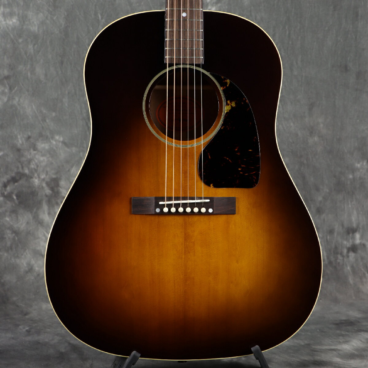 ■こちらの商品は実機画像を掲載しており、店頭未展示の倉庫保管品となります。出荷前に専任スタッフにより楽器の各部機能チェックを行っております。 Epiphone Inspired by Gibson Custom から奥田民生の最新シグネチャー・モデルがリリース！ 最新『Epiphone Inspired By Gibson Custom Tamio Okuda J-45』は、2024年にソロ音楽活動30周年を迎え、現在も国内のJ-Rockシーンを牽引し続ける奥田民生氏のエピフォンからの2本目となるシグネチャー・モデルです。 当モデルは、奥田氏愛用の1945年製J-45をベースに2021年にリリースされた『Gibson Tamio Okuda J-45』のエピフォン版で、奥田民生氏監修のもと制作されました。ギブソン・カスタムとエピフォンのコラボレーションにより誕生したエピフォンのプレミアム・シリーズ『Inspired By Gibson Custom』からリリースされ、ルックスからサウンドに至るまでギブソンに限りなく近づけたクオリティを、よりお買い求め安い価格帯で提供します。 ヘッド形状 『Epiphone Inspired By Gibson Custom Tamio Okuda J-45』の特徴として、エピフォンの“スクリプト＆バナー”ロゴがあしらわれた“オープンブック・ヘッドストック”と呼ばれるギブソンと同じヘッド形状があげられます。また、ヘッドに搭載されているチューナーも、ギブソンと同じクリームボタン・タイプを採用し、一見するとギブソンと見分けがつかないほどの再現性を持ちます。 サーマリートップ サイド＆バックにはマホガニー材、トップにはギブソンと同じ “サーマリー・エイジド加工” を施したシトカ・スプルース材が使用され、ボディ内部のスキャロップド・Xブレイシングと相まって、新品でありながら長年弾きこまれたヴィンテージギターを彷彿とさせる深みのあるサウンドを生み出します。 フィニッシュ トップとバックにシングルプライ・バインディングが施されたボディは、グロス・フィニッシュの光沢を若干抑えた “ニューヴィンテージ・グロス“ 仕上げを採用。 僅かに退色したカラーを再現した“ウォッシュド・ヴィンテージ・サンバースト“との組み合わせにより、 ヴィンテージの質感溢れるルックスになっています。ピックガードは、べっ甲色のクラシックなティアドロップ・シェイプで、J-45のルックスを引きたてます。さらに、サウンドホール周りのパーフリングは奥田民生氏愛用のJ-45と同じ7層になっており、究極までギブソンのオリジナルに近づけた拘り抜いた出来栄えとなっています。 ネック ワンピース・マホガニーのネックは、ギブソンと同様にダヴテイル・ジョイントでボディに接合され、奥田民生氏愛用の1945年製ギブソンJ-45をベースとした厚みのあるネック・プロファイルを採用。ヴィンテージ・ギブソンのフィーリングをお楽しみいただけます。 指板＆ブリッジ その他、ミディアム・フレットによる19フレット仕様のローズウッド指板には、マザー・オブ・パールのドット・ポジションマーク・インレイがあしらわれ、ローズウッドのレクタングギュラー・ブリッジ上のサドル、ナットとブリッジ・ピンには、それぞれボーン材を使用しています。 ピックアップ＆ケース 当モデルには、アンダーサドルのL.R.Baggs VTCピックアップとアクティブ・プリアンプが搭載され、ライブやスタジオでの演奏環境にも対応。さらに、”Inspired By Gibson Custom” のクラシックなロゴがプリントされた専用ハードケースが付属します。 エピフォンとギブソンの最高峰であるギブソン・カスタムのコラボレーションにより誕生したエピフォン最上位シリーズ『Inspired By Gibson Custom』からリリースされる最新『Epiphone Inspired By Gibson Custom Tamio Okuda J-45』は、ビギナーからプロフェッショナルまで満足のいくギブソン・クオリティと最高のサウンドをお届けします。 ■付属品：ハードケース、正規保証 ※ご購入いただいたご本人様に限り、メーカー規定の故障に対して保証が提供されます。保証修理受付の際は「ご購入時の領収書もしくは納品書」をご提示いただきます。 ■シリアルナンバー：25061500628※実物画像を掲載しておりますが、モニター環境によっては若干色合い・明るさが違って見える場合がございます。予めご了承くださいませ。 製品仕様 Shape | J-45 Top | Thermally Aged Sitka Spruce Back | Mahogany with Center Stripe Sides | Mahogany Bracing | Scalloped X-Bracing Binding | Single Ply, Top and Back Neck | One Piece Mahogany Neck Profile | Tamio Okuda 1945 J-45 Nut width | 1.73" / 44mm Fingerboard | Indian Rosewood Scale length | 24.75" / 628.65mm Number of frets | 19 Nut | Bone Inlay | Mother-of-Pearl Dot Bridge | Rosewood Rectangle, Closed Slot Pickguard | Tortoise Shell Celluloid/Acrylic Sandwich Tear Drop Tuners | Three-on-a-Plate Closed Back with White Button Plating | Nickel Under saddle pickup | L.R.Baggs VTC Controls | Soundhole Mounted Volume and Tone Case | Red Line Inspired Hardshell