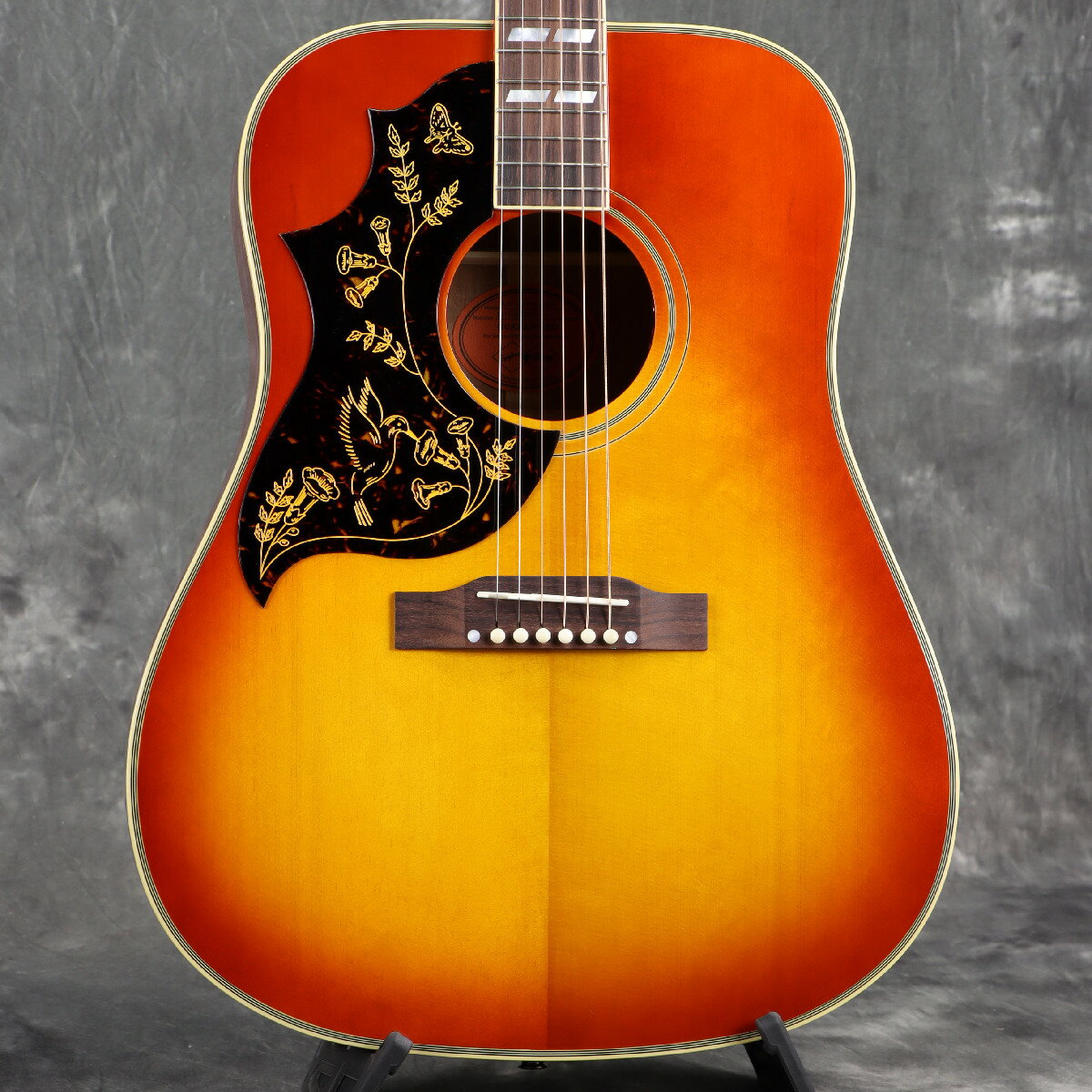 ■こちらの商品は実機画像を掲載しており、店頭未展示の倉庫保管品となります。出荷前に専任スタッフにより楽器の各部機能チェックを行っております。 Epiphone Inspired by Gibson Customから新モデルがリリース！ EpiphoneとGibson Custom Shopのコラボレーションによって製作されるEpiphone Inspired by Gibson Customコレクションは、2024年に大幅に刷新されました。 特に、方方から熱い要望があったにも関わらずなかなか実現することがなかった"Gibsonヘッド"が採用されたことは、多くのGibson/Epiphoneファンにとって非常にエキサイティングなことでした。 そして2025年、Epiphoneのトップラインとして高い評価を得続けているそのEpiphone Inspired by Gibson Customコレクションは、さらなるアップデートが施されます。 ウッドマテリアルやフィニッシュのリファインに加え、Gibsonアコースティックギターの歴史を語る上で欠かすことのできないモデル達が新たに加わることとなりました。 1960 Hummingbird Reissue Heritage Cherry Sunburst 1960年にギブソン初のスクエアショルダーアコースティックギターモデルとして登場したHummingbird。 音楽の新たな時代の幕開けと共に登場し、以来、キース・リチャーズやブライアン・ジョーンズ、エリック・チャーチ、J・マスシス、ジョー・ボナマッサ、レディオヘッドのトム・ヨークとジョニー・グリーンウッドなど、数多くのミュージシャンが愛用してきました。 エピフォンはギブソン・カスタム・ショップとのパートナーシップにより、ギブソン・カスタムからリリースされているヒストリック・コレクション1960 Hummingbirdモデルにインスパイアを受けて、生産初年度のアイコニックなハミングバードを再現したEpiphone 1960 Hummingbird Reissueを誇りを持って発表します。 ヴィンテージを彷彿とさせるディティールに拘り、サーマリー・エイジド加工が施されたシトカ・スプルースTop、ジェニュイン・マホガニーBack/Sideのオール単板ボディ、さらにクォーターソーン・スプルースを使用した伝統的なスキャロップドXブレーシングを採用しています。 ラウンド・プロファイルのネックは、サーマリー・エイジド加工が施された1ピース・ジェニュイン・マホガニーを使用し、ハミングバードの最大の魅力ともいえる温かく豊かなトーンを際立たせています。 今回のアップデートでローレルからローズウッドへとリファインされた指板にはマザー・オブ・パールのスプリット・パラレログラム・インレイが輝きます。 その他、ボディのマルチ・バインディング、キーストーン・ボタンのゴールド・ペグ、ハチドリが描かれた伝統的なピックガードシェイプなど、オリジナルを見事に踏襲しています。 もちろんヘッドストックはGibsonオリジナルの“openbook”ヘッドストック・シェイプが採用され、エイジングトナーが施されたクラウン・インレイとEpiphoneロゴが輝きます。 加えて、現代のプレイヤーのニーズと好みに応えるため、L.R.Baggs Element Bronze VTCプリアンプとアンダーサドル・ピエゾピックアップシステムを内蔵し、ライブパフォーマンスやスタジオレコーデイングなど様々なシチュエーションで活躍できます。 「Inspired by Gibson Custom」のロゴが施された、ヒストリカル・スタイル（Red Line）ハードシェルケースが付属します。 ※こちらのモデルは左利き用（レフトハンドモデル）です。 ■付属品：ハードケース、正規保証 ※ご購入いただいたご本人様に限り、メーカー規定の故障に対して保証が提供されます。保証修理受付の際は「ご購入時の領収書もしくは納品書」をご提示いただきます。 ■シリアルナンバー：24121500464※実物画像を掲載しておりますが、モニター環境によっては若干色合い・明るさが違って見える場合がございます。予めご了承くださいませ。 製品仕様 Shape | Hummingbird Top | Thermally Aged Solid Sitka Spruce Back and Sides | Solid Genuine Mahogany Bracing | Traditional Scalloped X-Bracing; Quarter-Sawn, Solid Spruce Binding | Multi-ply Top and Back, Single Ply Fretboard Neck | One-Piece Genuine Mahogany; Thermally Aged Neck Profile | Rounded Nut width | 1.74" / 44.196mm Fingerboard | Indian Rosewood Scale length | 24.75" / 628.65mm Number of frets | 20 Nut | Bone Inlay | Mother-of-Pearl Split Parallelogram Bridge | Traditional Belly Up; Rosewood Tuners | Epiphone Deluxe with Green Keystone Button Plating | Gold Electronics | L.R.Baggs Element Bronze VTC Controls | Soundhole Mounted Volume and Tone Case | Red-Line-inspired Hardshell with Inspired by Gibson Custom Graphics