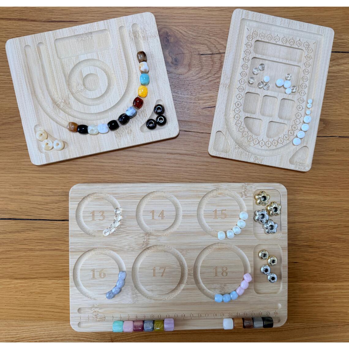 並べて、比べて、作りやすい。 用途で選べる竹製ビーズデザインボード。 ビーズや天然石を糸に通す前に、 色の組み合わせや並び順、完成イメージを確認できる 竹製のビーズデザインボードです。 「並べてみたら、色の順番を変えたくなった」 「ブレスレットのサイズ感を確認したい」 「細かなビーズや金具を分けながら作業したい」 そんなアクセサリー制作を、もっとスムーズに。 用途の異なる3タイプから、 作りたいアクセサリーや作業スタイルに合わせてお選びいただけます。 ■ TYPE A｜カーブレイアウト 自由に並べながら、完成イメージを確認したい方に。 複数のカーブ溝にビーズを仮置きできるため、 色の組み合わせや並び順、全体のバランスを 糸に通す前に確認できます。 ネックレスやブレスレット、 ビーズアクセサリーなどのレイアウトにおすすめです。 また、小さなトレイ部分には ビーズや金具などを一時的に置くことができます。 本体サイズ：約16.5×19.5cm 厚さ：約1cm ■ TYPE B｜目盛り＆トレイ 並べながら、細かなパーツも整理したい方に。 数字ガイド付きのレイアウト溝と、 複数のトレイスペースを備えたタイプです。 ビーズの配色や並び順を確認しながら、 金具・チャーム・小さなビーズなどを 種類ごとに分けて作業できます。 ビーズワークやアクセサリー制作で、 作業スペースをすっきり整えたい方にもおすすめです。 本体サイズ：約14×19.5cm 厚さ：約1cm ■ TYPE C｜ブレスレット6サイズ ブレスレット作りを中心に楽しみたい方に。 13・14・15・16・17・18cmの 6種類のサイズガイドを1枚にまとめました。 作りたいサイズの円形ガイドにビーズを並べることで、 配色やビーズの組み合わせ、完成イメージを 確認しながら制作できます。 天然石ブレスレット、パワーストーンブレスレット、 ビーズブレスレットなどの制作に便利です。 右側には、ビーズや金具を仮置きできる トレイスペースも付いています。 本体サイズ：約28.5×19cm 厚さ：約1cm サイズガイド：13 / 14 / 15 / 16 / 17 / 18cm ■ 糸に通す前にデザインを確認 一度糸に通してしまってから 「この色を入れ替えたい」 「もう少し違う配置にしたい」 となると、作り直しが必要になることも。 ビーズデザインボードなら、 まずビーズを溝に並べて全体を確認できます。 配色・順番・バランスを調整してから制作できるので、 初心者の方のアクセサリー作りにもおすすめです。 ■ ビーズが転がりにくい溝付き ビーズを置きやすいように溝が設けられているため、 机の上に直接並べるよりも作業しやすく、 制作途中のデザイン確認にも便利です。 ■ ナチュラルな竹製 自然な風合いを楽しめる竹素材を使用。 ハンドメイドスペースにもなじみやすい、 シンプルでナチュラルなデザインです。 【商品仕様】 商品名：ビーズデザインボード 素材：竹 内容：デザインボード 1枚 TYPE A 約16.5×19.5×厚さ1cm TYPE B 約14×19.5×厚さ1cm TYPE C 約28.5×19×厚さ1cm サイズガイド：13 / 14 / 15 / 16 / 17 / 18cm ■ こんな用途におすすめ ・ブレスレット制作 ・ネックレス制作 ・ビーズの配色確認 ・パーツの仮置き ・完成イメージの確認 ・ハンドメイドアクセサリー制作 ■ 竹製ならではのナチュラルな風合い 竹素材を使用した、自然な木目が魅力のデザインボードです。 作業用ツールとしてだけでなく、制作スペースにも馴染みやすいデザインです。 ■ ご購入前にご確認ください ※本体に刻印されている目盛り・数字は、制作時の目安としてご使用ください。 正確な計測を保証するものではありません。厳密なサイズ確認が必要な場合は、定規やメジャー等をご使用ください。 ※天然の竹素材を使用しているため、木目・色合い・節の位置などには個体差があります。 ※製造工程上、表面や刻印部分に多少の色ムラ、細かな傷、仕上がりの個体差が見られる場合があります。 ※商品サイズは測定方法により多少の誤差が生じる場合があります。