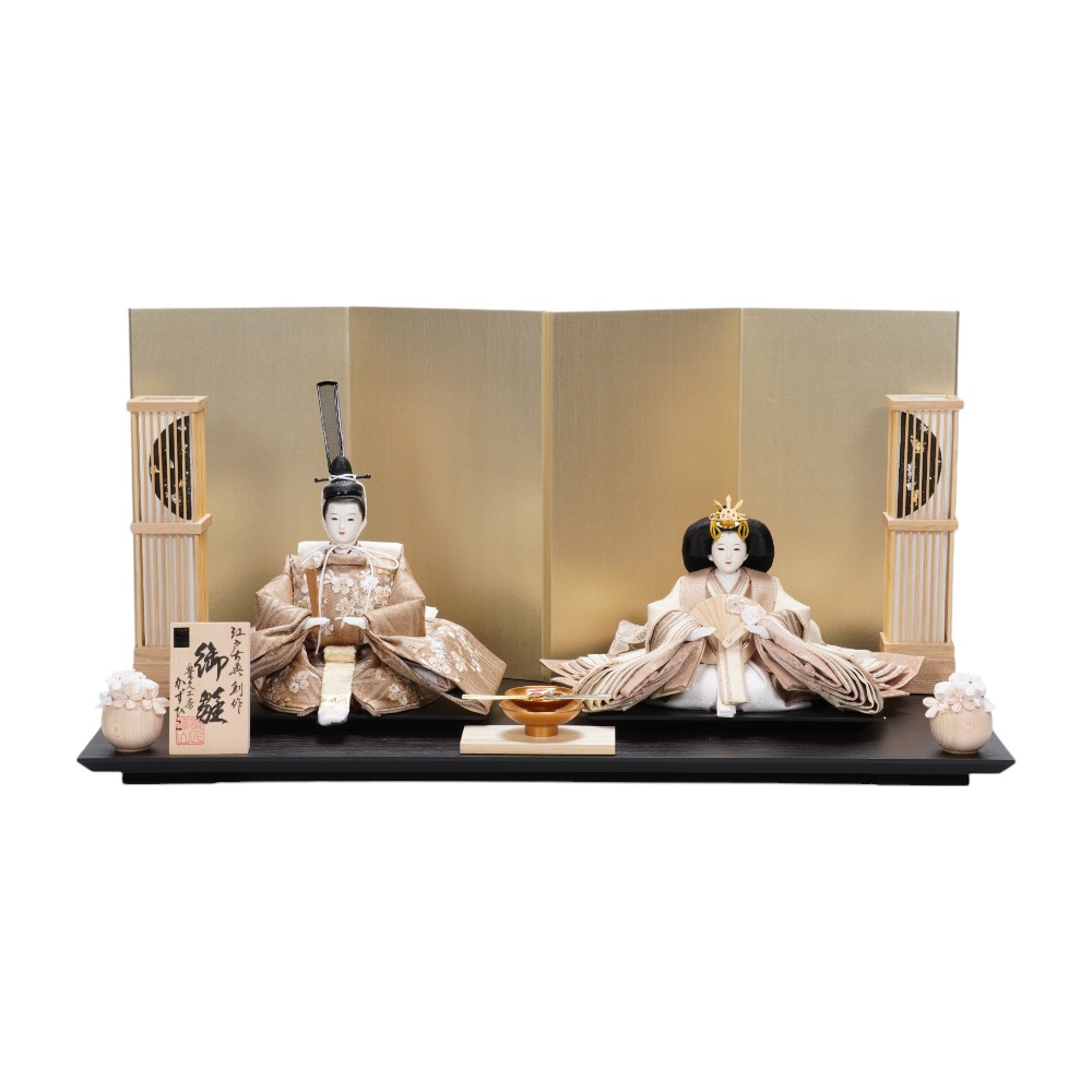 【製作】横山一彦 【頭師】熊倉基安 【規格】小三五親王 【仕様】木胴、木手 【装飾】木目飾り台、絹貼り屏風、コードレス行灯、御花、盃、毛氈 【寸法】幅60×奥行35×高さ30(cm) ※手作り品につき仕様が変更になる場合がございます。予めご了承くださいませ。 ※お使いのモニターの設定や発色により、実際の商品と色味が異なって見える場合がございます。 落ち付いたトーンの飾り台に、シンプルながらも深みのある屏風を組み合わせました。 色・ツヤの表情が異なるスズ箔を、一枚一枚手作業で和紙に配置し、古風な味わいに仕上げました。 さらに、川又絹を重ねることで箔の主張を抑え、華やかな色彩と光沢を加えた、高級装飾紙です。 〈横山一彦〉 昭和22年東京に生まれる。 初代(父)は、十軒店玉貞人形三代目「堀尾貞蔵」に師事した人形師「横山富久」。 昭和48年に父の元、雛人形の製作に従事。 平成14年に東京都知事認定の伝統工芸士の資格を取得。 平成15年台東区伝統工芸士の資格を取得。 着付けに高度な技術を要する「本着せ付け」の手法を体得する数少ない人形作家の一人である。 初代の志を受け継ぎながら、温故知新の精神をもって、現代の生活にも受け入れられるような人形を追求ています。 「伝統も守りつつ、新しい表現に挑戦したい。」 ひとつひとつに夢の広がる人形づくりをめざしています。