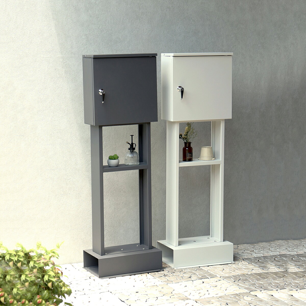 ■スタンドポスト Alda(アルダ) ポスト ダイヤル式 置き型ポスト 屋外 ■商品説明置くだけで使用可能なスタンド式。壁掛け式とは異なり面倒な施工の手間がかかりません。ゆうパケットポストや、ネコポスが投函可能です。鍵付きなので防犯面に安心です。また、スペアキーが1本付属しています。棚板が1枚ついており(固定棚)、お花や玄関周りの小物置きとして便利です。鍵部はハンドルレバータイプを使用しており、ハンドルの操作で、鍵の開閉を行わずとも扉を閉めておくことが可能です。「郵便受け本体」、「支柱」、「台座」の3パーツのみをボルトで固定する簡易組立の商品となります。郵便取り出し口内部にストッパーが付いているため、取り出し時に郵便物が前に落ちにくい設計となっております。土台部は、標準サイズのレンガ(21×10×6cm)を最大3個入れることが可能です(横向き×2、縦向き×1)。キー、アンカーボルトが付属しており、お客様で追加でご用意頂くものはなく、すぐにご使用いただけます。郵便受け本体は、落ち着いた色合いのダークグレーと、くすんだベージュのグレージュの2色からお選び頂けます。ガルバナイズド処理を施しているため、錆びにくくなっております。地面固定用のアンカーボルトが付属します。土台部にアンカーボルトを打ち込む穴があり、地面とポストを固定することも可能です。※防水塗装は施しておりませんので、軒下や屋根がある場所への設置を推奨致します。■サイズ本体サイズ：(約) 幅36cm ×奥行28 cm ×高さ114.5cmその他サイズ：投函口:(約)幅32.9cm × 奥行3.4cm 取出口:(約)幅33cm × 奥行12.9cm × 高さ31.3cm ■仕様金属(鉄)■耐荷重ボックス内：2kg■商品重量(約)9.9kg■組み立てお客様ご自身で要組み立て■生産国中国更新日20250612■スタンドポスト Alda(アルダ) ポスト ダイヤル式 置き型ポスト 屋外 ■