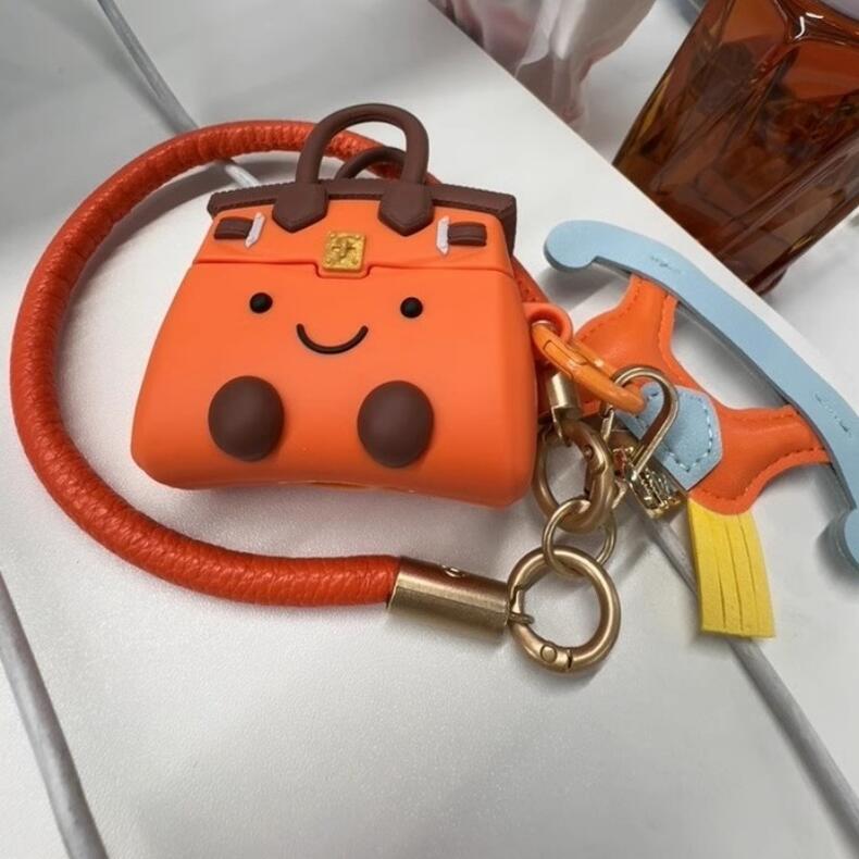 【送料無料】オレンジ色のハンドバッグ形微笑み顔AirPods用保護カバー 6サイズ アニメAirPodsケース イヤホン保護ケース 馬飾り付き 面白いAirPo...