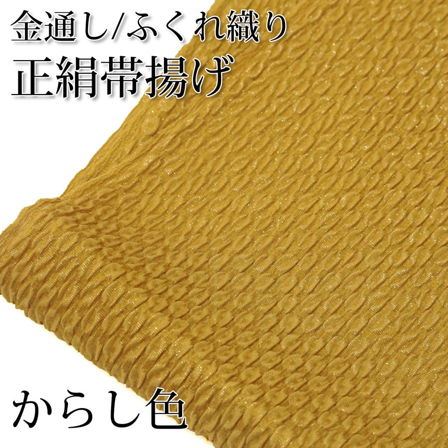 金糸が織り込まれたふくれ織の正絹帯揚げです。織物の郷、京都丹後地方で織り上げられた上質な国産帯揚げです。辛子色（からし色）の地色に金通しの糸が織り込まれています。光の当たり方や角度によって上品にキラキラと煌めいています。 成人式や結婚式の振袖、晴れ着などに最適です。 ＜サイズ＞ 約20×170cm ＜品質＞ 絹100% ※サイズは製造時期や入荷時期によって実際のサイズと多少異なる場合がございますが、帯揚げとしての使用用途としては差し支えない誤差です。 ※お客様のモニター環境などにより写真と実物の色目に若干の差異が生じる場合あります。予めご了承ください。