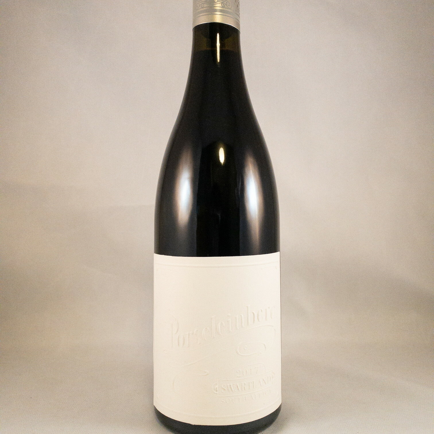 Porseleinberg Syrah / ポルセレインベルグ　スワートランド・シラー 2017/ 南アフリカ / スワートランド/シラー種 / カーリー・ロウ / プレゼント / ギフト / ワイン好き / 2017ヴィンテージチャートとても良い年 / 料理とのマリアージュ / スパイス / 肉料理 / ソムリエのいるワインショップ / wsetレベル3所有者のいるワインショップ&nbsp; /赤ワイン / WA95点 / プラッターズ5つ星 / ジャンシスロビンソン18/20点 / ティムアトキン98点&amp;格付け1級 / デキャンターにて南アフリカのシラーTOP3 /&nbsp;Porseleinberg&nbsp;-ポルセレインベルグ-スワートランド・インディペンデント・プロデューサーズの主要メンバーであり、そのメンバーらから”レジェンド”と呼ばれるカリー・ロウ氏により立ち上げられたワイナリー。パーカー5つ星生産者ブーケンハーツクルーフが始めた「プレミアム・シラー」醸造家は、元タルバッハ・マウンテンのワインメーカーの「カーリー・ロウ氏」が努めます。醸造設備は、カーリーの事務所から約100mほど離れた場所にあり、フーダーと卵型のコンクリートタンクで丁寧に醸造されます。カーリーのいるこの地までの道のりは平坦なものではなく、果てしない荒野の中、赤土の土煙をあげて走り抜け、ようやくたどり着きます。※2018年9月 ケープワイン2018会場内にてお会いしました！！インポーターさんは、はるばるケープタウンから2時間以上もかけて疾走し、ポルセレインの丘で迎えてくれるカーリー・ロウは、まさに、このワインの用心棒という印象の体格で、このワインからは連想できないほど、肉厚の手で握手して迎えられたのが印象的だったと言います。作るワインはワイン名に冠されたスワトランドのポルセレインベルグの丘にある畑のブドウから作るシラー1種類のみという見事な潔さです。2010年が初ヴィンテージでしたが、その評判は瞬くままに国内のみならず国際的な評価を上げ、今となってはカルト的人気を誇るワインとなりましたワインラベルは年代物のドイツ、ハイデルベルグ社製活版印刷機で自身が一枚一枚仕上げるというこだわり様です。 ブドウは全て手摘みされ全房のままコンクリートタンクに移され足踏みされ自然醗酵。【限定数】ポルセレインベルグ シラー 2017容量：750mlアルコール度数：13.6%2017年は現地でも驚くほどの干ばつで、年間を通して例年の半分ほどの降雨量しかなく 「a hell of a challenge／地獄の挑戦」と言われたほど乾燥した年。非常に豊かなアロマは例年以上にベリー系の魅力に溢れており、フィンボス（西ケープ州特有の野生の植物）やプロヴァンスを思わせるハーブ香、砕いた黒コショウ、僅かにお香や木炭などのニュアンスが感じられ、見事なまでに豊かで妖艶さを醸し出しています。味わいは、ピュアで深味のあるベリー系果実の味わいが幾重にも重なり、このワインの特徴でもある非常にきめ細かいタンニンと、片岩質土壌由来の美しいミネラル感が見事な骨格を形成しており、複雑でパワフルな印象の中に、とても洗練された趣があります。