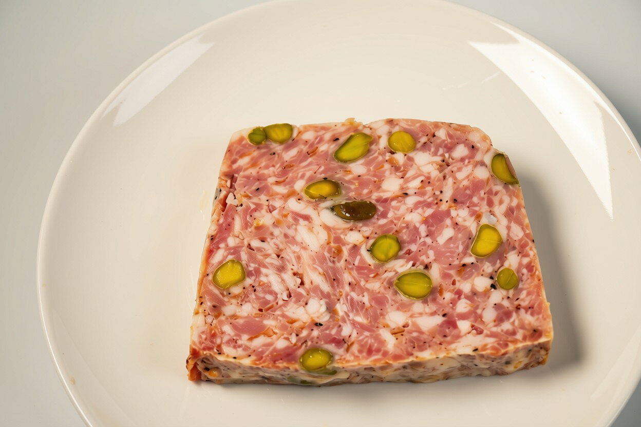 良質な豚肉を使用し、ソテーオニオンの甘みとスパイスの風味、ピスタチオの食感をバランスよく仕上げたポークパテ。濃厚でありながら食べやすく、ワインとの相性も抜群です。前菜やパーティー、おもてなしの一品としておすすめです。 原材料：豚肉（輸入）、ソテーオニオン、ピスタチオ、食塩、香辛料、砂糖／リン酸塩（Na）、pH調整剤、調味料（無機塩）、発色剤（硝酸K、亜硝酸Na）、保存料（ポリリジン）、ユッカ抽出物、（一部に卵・大豆・ピスタチオ・豚肉を含む） 栄養成分：エネルギー：320kcal　/たんぱく質：12.6g　/脂質：29.1g　/炭水化物：3.4g　/食塩相当量：1.6g アレルギー原料：卵、大豆、ピスタチオ、豚肉良質な豚肉を使用し、ソテーオニオンの甘みとスパイスの風味、ピスタチオの食感をバランスよく仕上げたポークパテ。濃厚でありながら食べやすく、ワインとの相性も抜群です。前菜やパーティー、おもてなしの一品としておすすめです。 原材料：豚肉（輸入）、ソテーオニオン、ピスタチオ、食塩、香辛料、砂糖／リン酸塩（Na）、pH調整剤、調味料（無機塩）、発色剤（硝酸K、亜硝酸Na）、保存料（ポリリジン）、ユッカ抽出物、（一部に卵・大豆・ピスタチオ・豚肉を含む） 栄養成分：エネルギー：320kcal　/たんぱく質：12.6g　/脂質：29.1g　/炭水化物：3.4g　/食塩相当量：1.6g アレルギー原料：卵、大豆、ピスタチオ、豚肉