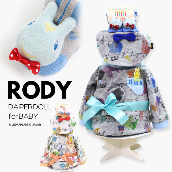 〇おむつドールの内容〇 Rody/ロディ ロンパース1点 Rody/ロディ スタイ　1点 Rody/ロディ ソックス　1点 おむつ/パンパース（テープタイプ21枚/パンツタイプ16枚） ・おむつケーキ ・オムツケーキ ・ダイパーケーキ ・女の子 ・出産祝い ・プレゼント ・1歳 誕生日 ・ハーフバースディ ・百日祝い ・かわいい ・おしゃれ ・ベビーシャワー ・カバーオール花柄のシフォンスカートがお洒落なカバーオールです:*♪☆ 1枚でセットアップ風のお洒落コーデの完成。♪♪ ふんわり華やかなデザインでプレゼントにもピッタリ＾＾♪ ★カバーオール素材 本体：ポリエステル　65％・綿　35％ 衿ぐり・袖口・足口：ポリエステル　63％・綿　33％・ポリウレタン　4％ スタイ：ポリエステル　65％・綿　35％ リボン：綿　100％ 〇おむつドールの内容〇 Rody/ロディ ロンパース1点 Rody/ロディ スタイ　1点 Rody/ロディ ソックス　1点 おむつ/パンパース（テープタイプ/21枚・パンツタイプ16枚）