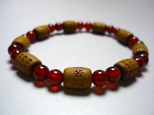 般若心経の全文が刻まれたブレスレット白檀の木は、木から発せられる優しい香りがあります。身に着ける方を優しい芳香で包み込み、気持ちを和らげてくれるでしょう。香木の芳香漂う白檀を素材に使用し彫り上げられた逸品です。また、一玉ごとに彫られているお経は、順番に読むと般若心経になります。般若心経は、「色即是空(しきそくぜくう)」、つまりこの世のすべてのものは「空（くう）」であり、それがこの世の真実である、ということをしめしたお経であると云われています。こちらは瑪瑙で仕立てております。★玉の大きさ・種類・親玉　直径が約1.0cm×0.8cm（白檀）・主玉　直径が約0.7cm（瑪瑙）内径：約18センチ【smtb-TK】　