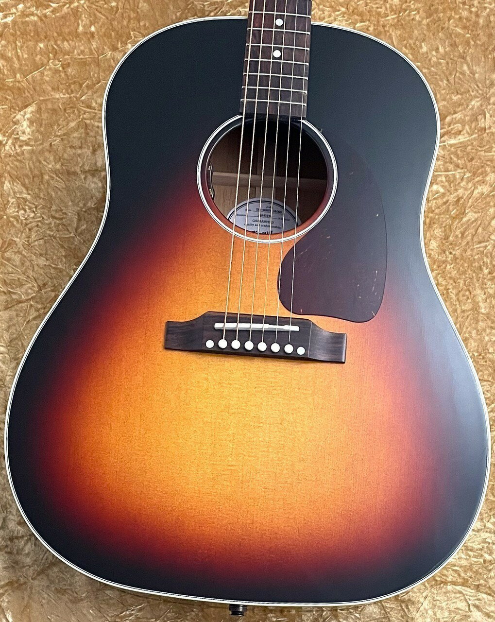 【G-CLUB SHIBUYA限定企画！タリアカポプレゼントキャンペーン実施中！】 対象の新品Gibsonアコースティックををお買い上げの方にUSA製高級カポタスト、Thalia Caposプレゼント！ ギターの雰囲気が格段とランクアップ！お客様の「相棒」がより輝きを放ちます。 ネックシェイプに合わせてネックとの接地面を換装できます！ ※G-CLUB SHIBUYA限定のキャンペーンとなります。 ※無くなり次第終了致します。 ※カラー等の仕様はお選びいただけません。予めご了承くださいませ。 【ショッピングクレジット無金利】＆【超低金利キャンペーン】48回払いまで金利手数料0%!!　 ------------------------------------------------------------------------- 国内外問わずに多くの人の「相棒」として名を馳せるGibson Acoustic。 アコースティックサウンドとはどんなイメージの音なのか？という疑問に対してGibsonサウンドを聴くと、まさに「この音」と感じる方も多いでしょう。 ブルースやロックが得意分野ということを根底に置き、国内ではフォークソング全盛期にも著名なアーティストの相棒として活躍してきました。皆様が愛聴されている往年の「名曲」と呼ばれる楽曲の多くには、Gibsonサウンドの遺伝子が組み込まれていると思います。 音源だけではなくステージ上のアーティストやCDのジャケット、雑誌の一コマなど至る所に常にGibsonは存在していました。ふとした瞬間に目に入りそこから憧れを持ち始めた方が多いのではないでしょうか？ そういった「ロマン」や「憧れ」を年代を問わずに常に持たせてくれるのがGibson最大の魅力だと思います。 あの時憧れたロマンの塊を是非手にしてみてください。 ------------------------------------------------------------------------- 時は1942年、後世までに伝わるフラットトップの大名作であるJ-45が誕生。得意なジャンルはありつつも、多岐に渡る分野の環境でその人の「相棒」として地位を確立してきました。 J-45最大の長所は何と言っても弾き語りに適しているギターであることでしょう。まず、サウンドを聴いてみると低音〜中音域にかけて如実に前に出ている印象があると思います。Gibson特有の暖かみ溢れるサウンドですね。 他ブランドの煌びやかさ溢れる高音域はありませんが、これが弾き語りに最高にマッチする理由の1つです。 歌声とギターのサウンドが邪魔することなく整合性が取れており、短いスケールから生まれるザクザクとした感触とすっきりとした残響感が合わさることによっていわゆる「あの音」が作られるのです。しっかりとギターサウンドの主張は存在しつつも、決して歌声の邪魔ををしないバランスの良さはまさに黄金比であると言えるでしょう。 弾き語りが得意分野である理由はサウンドだけではありません。先述したようにスケールが短い点に加えて、ナット幅も狭くなっているので演奏性は抜群。加えて丸みを帯びた絶妙なグリップ感はプレイヤーの皆様にとって、気持ちの良い弾き心地を与えてくれると思います。 ------------------------------------------------------------------------- 今回のモデルは日本国内限定で生産されたエクスクルーシブモデルのうちの1つ。トライバーストと名付けられた赤身の強いサンバーストが非常に印象に残るモデルです。 同じカラーリングでVOS仕様の物もありますが、今回は美しいグロスフィニッシュ仕様。アコースティックギターの楽しみ方の1つとして、長い時間をかけて新品を1から自身の手で育て上げていくという面があります。まさに将来性が楽しみな1本です。 【#22843196】 ピックでかき鳴らした際に生まれる骨太かつパワフルなサウンドはもちろんですが、個人的には指弾きで鳴らした際のGibson特有の暖かさが非常に印象に残ります。バンドサウンドに混ぜて使ってもサウンドが1歩後ろに引いてくれるので、アコースティックサウンドの主張が激しくなりすぎないサウンドメイクが出来ると思います。オールラウンダーに憧れのJ-45を使い倒したい方に是非おすすめしたい個体です。 この機会に是非ご検討くださいませ。 オリジナルハードケース、保証書付属 【Spec】 ・Top:Spruce ・Side&Back:Mahogany ・Bracing:Traditional hand-scalloped X-bracing ・Neck:Mahogany ・Fingerboar:Rosewood ・Bridge:Traditional belly up, Rosewood ・Scale:24.75" (628mm) ・Nut Width:1.725"(43.8mm) ・Electronics:L.R.Baggs Element VTC ・Finish:Nitrocellulose --------------------------------------------- ※実物の色合いは掲載画像と若干異なる場合がございますので、あらかじめご了承ください。 ※通信販売をご利用のお客様は、必ず「通信販売のご案内」をご確認の上ご利用ください。 ※掲載商品売却の際、迅速にサイトから削除するよう心がけておりますが、 ショッピングページの更新にタイムラグが生じる場合がございます。 万一ご注文後に売り切れとなっておりました場合は、誠に恐れ入りますがご容赦ください。 ※店舗での試奏やご購入をお考えの方は事前にTEL、またはメールにてご連絡いただければ確実です。 --------------------------------------------- クロサワ楽器 G-Club 渋谷 5階　アコースティックギター・クラシックギターフロア Martin,Gibson,Taylor,Takamine,Headway,エレガットを中心に 国内外の有名ブランドを幅広く取り揃えている店舗です。 3万円〜180万円までの価格帯で初心者から上級者の方まで ご満足いただけるラインナップで皆様をお待ちしております。 全ての在庫品は5階で湿度・温度管理を徹底しております。 専属リペアマン常駐店の為、アフターサポートも充実しておりますので どなたでも安心してご利用いただけます。 電話:03-3462-9211 E-mail:g-shibuya@kurosawagakki.com 【高価買取キャンペーン中】 只今 アコースティックギターの高価買取キャンペーンを実施中です。 Gibson,Martin,Taylor,MATON,Headwayを中心に、 他店よりも高い買取金額でお受けいたします。 メール【g-shibuya@kurosawagakki.com】でもご相談を承っております。 今は弾かなくなった、もしくはステップアップ買い替えの為に、 大切なギターをお売りするお客様は 是非一度、お気軽にお問い合わせ下さい。 ------------------------------------------------------------------ 【無金利ショッピングクレジットキャンペーン中】 ただいま最大48回払いまで分割無金利にてご購入いただけます。 ご注文の際に決済方法の【ローン】にチェックを入れご注文下さい。 当店から【JaccsWebクレジット】お申込みメールをお送りさせて頂きます。 ご不明な点は是非お問い合わせ下さい。 〜通信販売をご利用のお客様へ 〜 掲載商品売却の際、迅速にサイトから削除するよう心がけておりますが、 ショッピングページの更新にタイムラグが生じる場合がございます。 万一ご注文後に売切れとなっておりました場合は、誠に恐れ入りますがご容赦ください。 店舗での試奏やご購入をお考えの方は事前にTEL、またはメールにてご連絡いただければ確実です。 -------------------------------------------------------------------------------- 黒澤楽器店 G-CLUB SHIBUYA 〒150-0043 東京都渋谷区道玄坂2-29-17 Tel: 03-3462-0261（エレキギター） 03-3462-9211（アコースティックギター） 03-3462-0271（ベース） 営業時間:11:00〜20:00