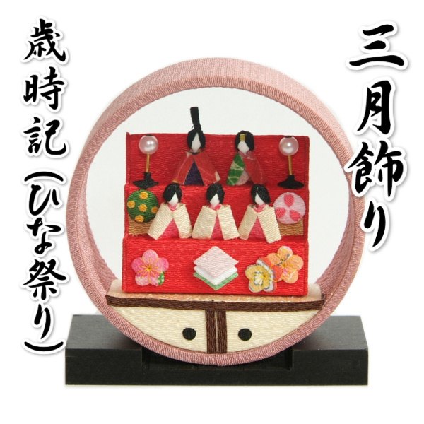 桃の節句祝いなどに飾っていただく可愛らしい室内用のひな飾りです。 京都の四季の移ろいを丸いドールハウスにギュッと詰め込み可愛らしい町屋箱に入れた日本の古き良き情景を彷彿とさせる京の歳時記町屋飾りになります。 飾り輪部分の直径が約11.5cmくらいのコンパクトな卓上サイズになりますのでひな人形などと一緒に飾って頂いたり食卓や玄関などに飾って頂くにも最適です。 輪っか状の中に見えるのはひな人形飾りを愛でながら過ごす日常、その中に成長と幸せを感じられる古来日本より受け継がれる風景を表しています。 モチーフはすべて縮緬飾りになり、生地表面の凹凸が立体感のある生地感になり可愛らしさだけじゃなく高級感もあります。 飾り台は天然の木材などを使用していますので木目による柄やへこみなどは御了承下さい。 組み立て不要の完成品になりますので箱から出して飾り台に乗せて頂ければすぐに飾って頂けます。仕様詳細 商品番号 kazari-m-h01 寸法 輪　直径約11.6cm、奥行（厚み）約4cm飾り台　幅約12cm、奥行約4.5cm、高さ約1.5cm 色目 輪部分　ピンク色台座　黒色 素材 モチーフ：レーヨン、ポリエステル 御注意点 ※水気などが含まれたり強く擦るなどした場合に色落ちや色移りする事が御座いますので御注意下さいませ。※商品の部品がパーツによって細かくなることが御座いますのでお子様の手の届かない所での保管や展開をして頂くようお願い致します。 輪っか状の中にひな人形などの御雛飾りのモチーフが入った卓上飾りです！！ 飾りは縮緬生地になっていますので生地感も高級感があります！ 飾り台も付いています！ 組み立て不要の完成品になりますので付属の飾り台に乗せて頂くだけですぐに飾れます 京の町屋を模した可愛らしい箱にお入れ致します！ 箱に入れるとなんとも言えない風情がある仕様になり、贈り物としても喜ばれると思います！