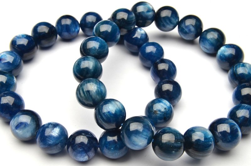 材質カイヤナイト 10mmサイズ約10mm（±0.5mm）腕周り約16cm(伸縮性有り)重さ約38g特徴・意味カイヤナイトは、ギリシャ語で青色を意味する "kyanos" に由来して名付けられました。和名には、くすんだ青色を意味する "藍" という文字が含まれており、石のもつ青色の美しさがこの石の最大の特徴となっています。主な産地はブラジルですが、日本や世界各地でも産出しています。カイヤナイトは依存心や甘えをなくし、独立心や探究心を強めます。カイヤナイトは固定概念を外したり悪習慣を遠ざけることによって、持つ人の世界観を確立する事を助ける石と云われています。強く霊性やインスピレーションに働きかけ、様々な考え方や霊的エネルギーを混乱することなく、一度に扱えるようにする為のサポートをします。現実面も含め、曖昧な物事を明確に、整理整頓するような感覚に近いかもしれません。実際カイヤナイトは整理整頓ができない人、捨てられない人にもオススメの石です。【金運・仕事運】【学業成就】BL::0910-002004k