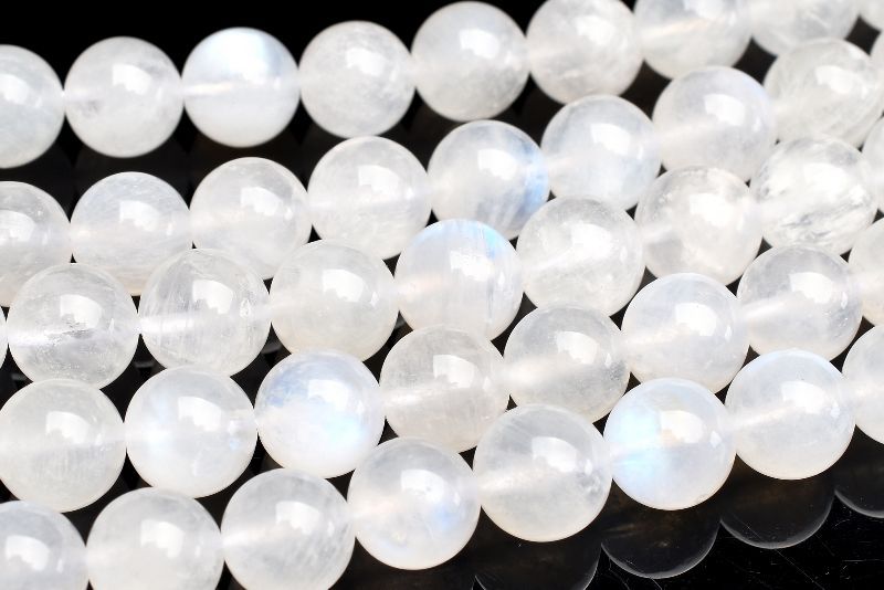 材質ムーンストーン 8mm 産地：インドサイズ約8mm(±0.5mm)重さ約37g特徴・意味やわらかな乳白色にブルーシラーが神秘的に浮かぶ、ムーンストーンの連ビーズです。ムーンストーンは長石（フェルドスパー）という鉱物グループの一種。長石グループの石には、ラブラドライト、サンストーン、アマゾナイトなどがあり、同じ仲間とは思えないほど多種多様です。ムーンストーンはオーソクレース（正長石）を主とし、アルバイト（曹長石）を含むものをいい、この二種類の長石の層が重なり合って、光の内部反射と干渉が起こり、「シラー（シーン）」と呼ばれる幻想的な光の効果を見ることができます。この光こそがムーンストーンの最も特徴的な魅力でもあり、名前の元となるイメージをかきたてたのだと思います。一般的に知られるムーンストーンは乳白色、または半透明の物が多いようですが、他にもオレンジ、ピンク、イエロー、グリーン、灰色がかったグリーン、灰色、茶色、褐色など様々な色があります。ムーンストーンは6月の誕生石。その昔、この石は月の輝きが結晶した石だと信じられており、月の魔力の化身として神聖視されていました。古代インドの人々は、ムーンストーンを「聖なる石」として崇め、お守りとして身に着けていたそうです。夜道を照らす月明かりのように、真実を授け、危険から身を守る力を与えてくれると考えられていたのでしょう。なお、ムーンストーンは流通名となっており、正式な鉱物名はホワイトラブラドライトです。