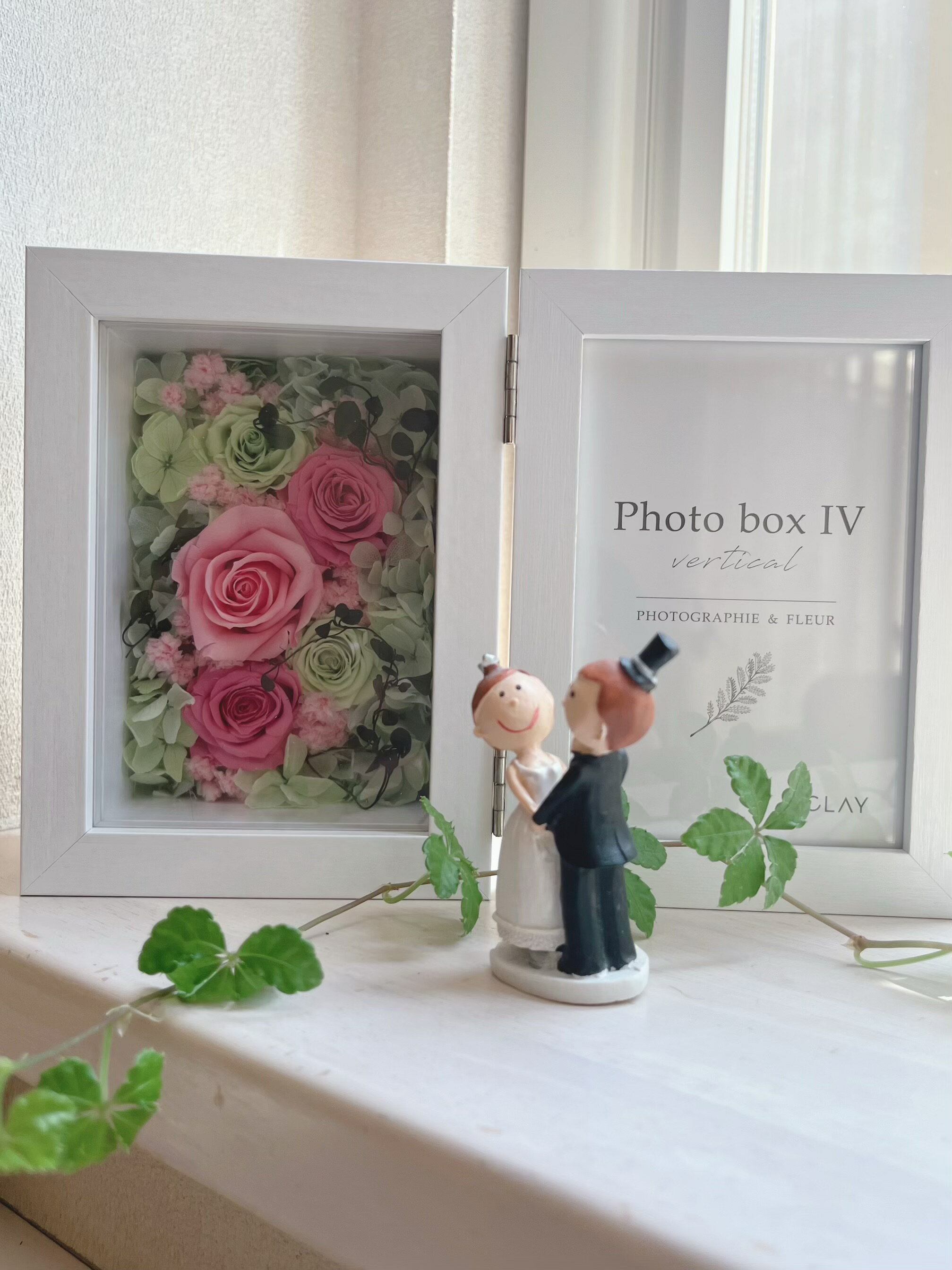 ピンクとグリーンのバラがとっても可愛いフォトフレームです。 特別な日の贈り物にぴったりで、幸せ感がいっぱい詰まっています。お誕生日や結婚祝い、出産祝い、母の日、敬老の日、クリスマス、退職、卒業など、さまざまなシーンで喜ばれること間違いなし。大切な思い出を彩るこのフォトフレームで、心温まる瞬間を演出してみませんか？ Lサイズの写真、はがきサイズの写真を入れられます。 ガラスカバー付きですので、ホコリの心配もなくお花も長く楽しめます。 使用花材:プリザーブドフラワー ( バラ　あじさい　かすみ草) フォトフレーム:MDF(木材)に紙貼りを施しており、水に弱いためお手入れの際には乾いた布をご使用下さい。 サイズ:広げた状態　横22 　奥行き6.5 高さ15センチ 写真 L判に対応 プリザーブドフラワーですので水をかけないで下さい。 縦置きフォトフレームこちらから大切な思い出をお花と共に〜