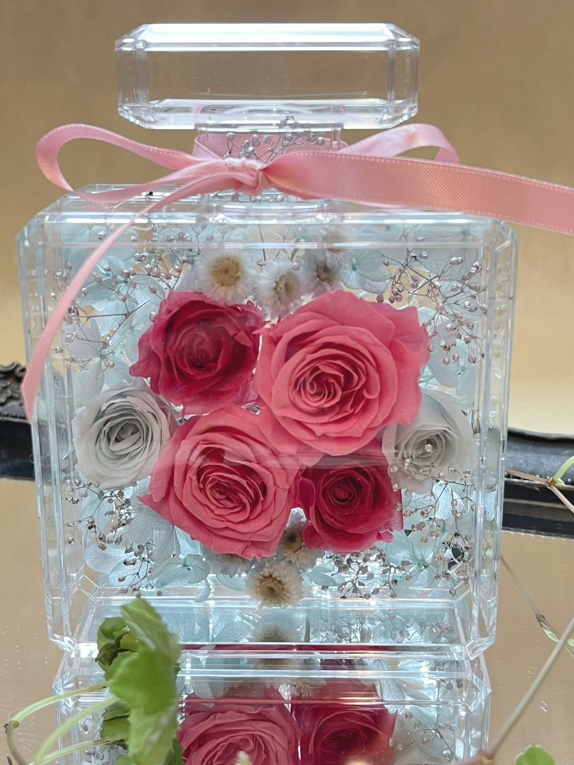透明感抜群のアクリル香水瓶に、ピンクとブルーのバラが美しくアレンジされたプリザーブドフラワーです。 心と体を癒す効果があるとされるこの色合いは、エネルギーチャージにぴったり。お誕生日や結婚祝い、母の日などの特別なギフトに最適です。真四角のデザインがスタイリッシュで、どんなインテリアにもマッチします。大切な方へのお礼や退職祝いにも喜ばれること間違いなしです！ 撮影用小物は価格に含まれていません。 使用花材:プリザーブドフラワー ( バラ　あじさい　かすみ草 　イモーテル) 香水瓶:アクリル樹脂 サイズ:幅10×奥行き6 高さ13.5センチ　 プリザーブドフラワーですので水をかけないで下さい。 ミラートレイ　ブラックゴールドは、こちらから 他の丸い香水瓶アレンジはこちらから 撮影用小物は価格に含まれていません。 使用花材:すべてプリザーブドフラワー を使用しています。 ( バラ　あじさい　かすみ草 ) 香水瓶:アクリル樹脂 サイズ:幅10×奥行き6 高さ13.5センチ　 プリザーブドフラワーですので水をかけないで下さい。 ミラートレイ　ブラックゴールドは、こちらから 他の丸い香水瓶アレンジはこちらから ミラーコースーター(L)は、こちらから