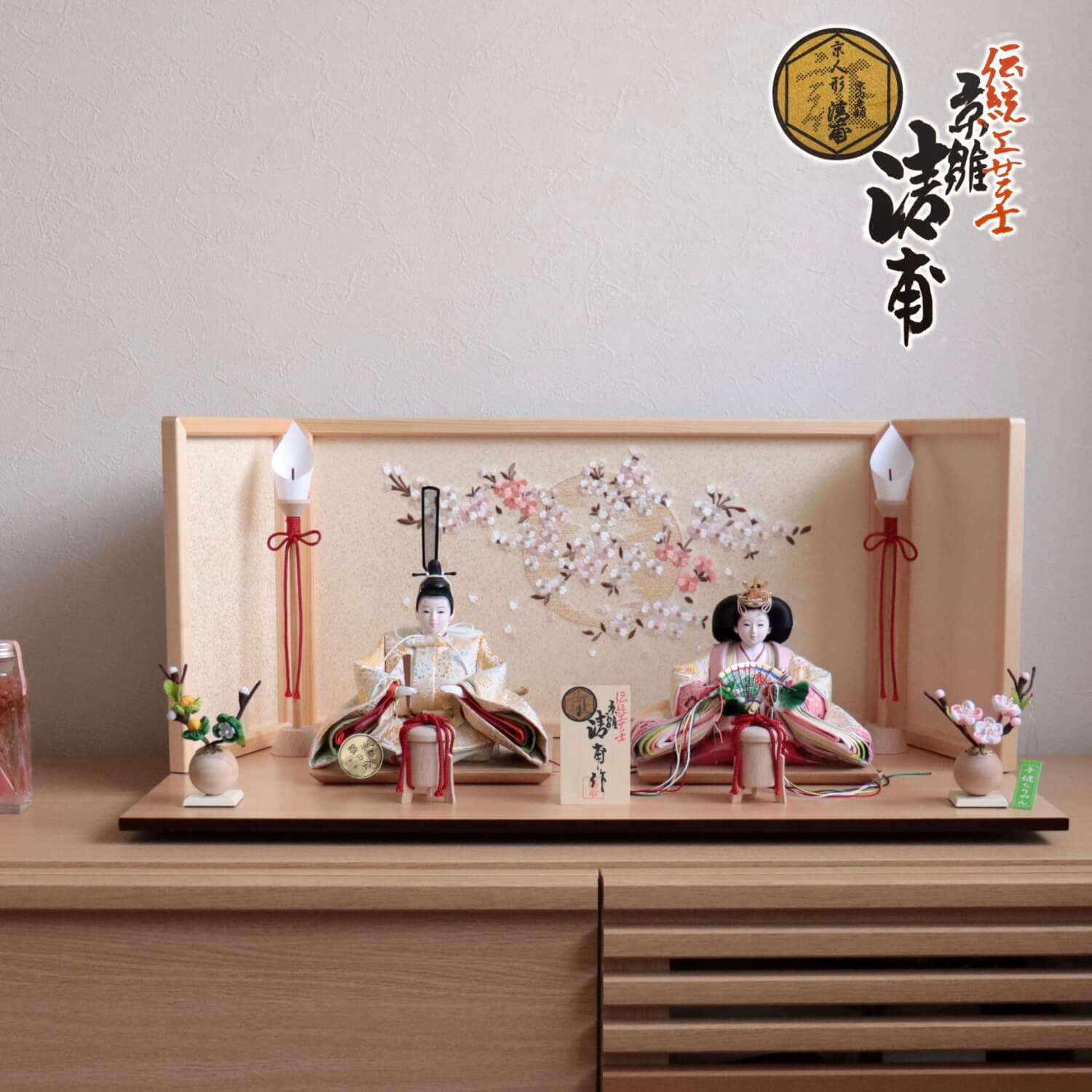 サイズ 幅 65cm × 奥行 35cm × 高さ 29cm ＜伝統工芸士 小西清甫＞ 創業は明治22年、初代・奥山弥三郎が人形づくりを始める。昭和39年に奥山健二郎が二代目を継承。 昭和43年、小西清一が三代目を継承し、昭和61年、通商産業大臣表彰、伝統的工芸品産業功労者表彰を受賞。 その翌年に現代表の小西司郎が四代目を継承。 平成13年には『清甫』として、130 年に渡る活躍と数々の伝統的かつ独創的な人形制作活動が認められ、京都府・京の老舗百年優良店認定を受ける。 平成19年、小西司郎が京都府伝統産業優秀技術者賞、翌年に伝統的工芸品産業功労者表彰を受賞。平成27年には瑞宝単光章を受賞する。 ＜ 瑞宝単光章勳章受章 ＞ 令和二年秋の叙勲にて、京都・武久寛宗「佐治完三」がこれまでの京人形業界への多大なる功績が認められ、瑞宝単光章勲章を受章しました。 京都西陣織「誉勘商店(こんかんしょうてん)」 初代誉田屋勘兵衛が没したのが1761年という記録が過去帳に残り、創業は江戸宝歴年間前と伝わる。 現在の当主松井幸生は13代目にあたり、250年以上受け継がれた伝統、業績を忘れること無く日々研鑽を怠らない。 250年以上もの時が流れようとも、正絹しかも西陣織という“Made in 京都”にこだわり続ける、京都を代表する金欄専門店。 250年の歴史の結晶であるこの金欄を惜しげもなく使った雛人形、五月人形を直に御覧になってみてください。 その光沢、風合いは貴方の視覚を存分に楽しませ、肌触りはあなたの常識を易々と超えるでしょう。 京都西陣織「大嶋金襴(おおしまきんらん)」 最高級正絹西陣織に特化した金襴商。昭和58年、実父である大嶋喬が1800年代後半より続く京都の老舗金襴卸問屋で約30年勤めた後に独立し「大嶋金襴」を設立。現代表の大嶋浩之は二代目。その納品先は著名人形職人のみならず、本山級神社仏閣、人間国宝級刀匠など多岐に渡る。本金や手織をはじめとする最高級正絹西陣織に特化した金襴商。 ＜ 京製本革 清水焼石帯 ＞ 束帯装束(公家の正装)を身に着ける際のベルトの様な役割を果たす「石帯(せきたい)」。 雛人形の殿の腰の部分に巻かれていますが、ビニールにプラスチック、海外製のものがほとんど。 最高級は京製の本革に京都清水焼の石(緑色)が付いたものになります。サイズ 幅 65cm × 奥行 35cm × 高さ 29cm ＜伝統工芸士 小西清甫＞ 創業は明治22年、初代・奥山弥三郎が人形づくりを始める。昭和39年に奥山健二郎が二代目を継承。 昭和43年、小西清一が三代目を継承し、昭和61年、通商産業大臣表彰、伝統的工芸品産業功労者表彰を受賞。 その翌年に現代表の小西司郎が四代目を継承。 平成13年には『清甫』として、130 年に渡る活躍と数々の伝統的かつ独創的な人形制作活動が認められ、京都府・京の老舗百年優良店認定を受ける。 平成19年、小西司郎が京都府伝統産業優秀技術者賞、翌年に伝統的工芸品産業功労者表彰を受賞。平成27年には瑞宝単光章を受賞する。 ＜ 瑞宝単光章勳章受章 ＞ 令和二年秋の叙勲にて、京都・武久寛宗「佐治完三」がこれまでの京人形業界への多大なる功績が認められ、瑞宝単光章勲章を受章しました。 京都西陣織「誉勘商店(こんかんしょうてん)」 初代誉田屋勘兵衛が没したのが1761年という記録が過去帳に残り、創業は江戸宝歴年間前と伝わる。 現在の当主松井幸生は13代目にあたり、250年以上受け継がれた伝統、業績を忘れること無く日々研鑽を怠らない。 250年以上もの時が流れようとも、正絹しかも西陣織という“Made in 京都”にこだわり続ける、京都を代表する金欄専門店。 250年の歴史の結晶であるこの金欄を惜しげもなく使った雛人形、五月人形を直に御覧になってみてください。 その光沢、風合いは貴方の視覚を存分に楽しませ、肌触りはあなたの常識を易々と超えるでしょう。 京都西陣織「大嶋金襴(おおしまきんらん)」 最高級正絹西陣織に特化した金襴商。昭和58年、実父である大嶋喬が1800年代後半より続く京都の老舗金襴卸問屋で約30年勤めた後に独立し「大嶋金襴」を設立。現代表の大嶋浩之は二代目。その納品先は著名人形職人のみならず、本山級神社仏閣、人間国宝級刀匠など多岐に渡る。本金や手織をはじめとする最高級正絹西陣織に特化した金襴商。 ＜ 京製本革 清水焼石帯 ＞ 束帯装束(公家の正装)を身に着ける際のベルトの様な役割を果たす「石帯(せきたい)」。 雛人形の殿の腰の部分に巻かれていますが、ビニールにプラスチック、海外製のものがほとんど。 最高級は京製の本革に京都清水焼の石(緑色)が付いたものになります。